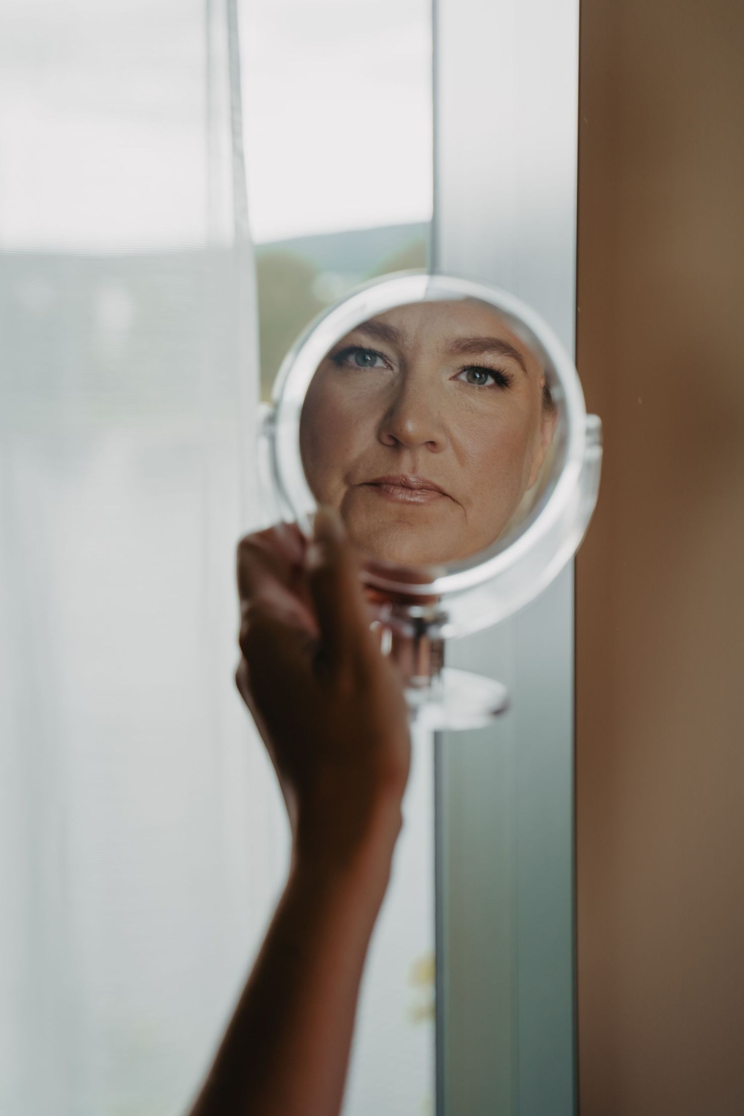 Reflection in a round makeup mirror showing beauty preparation.