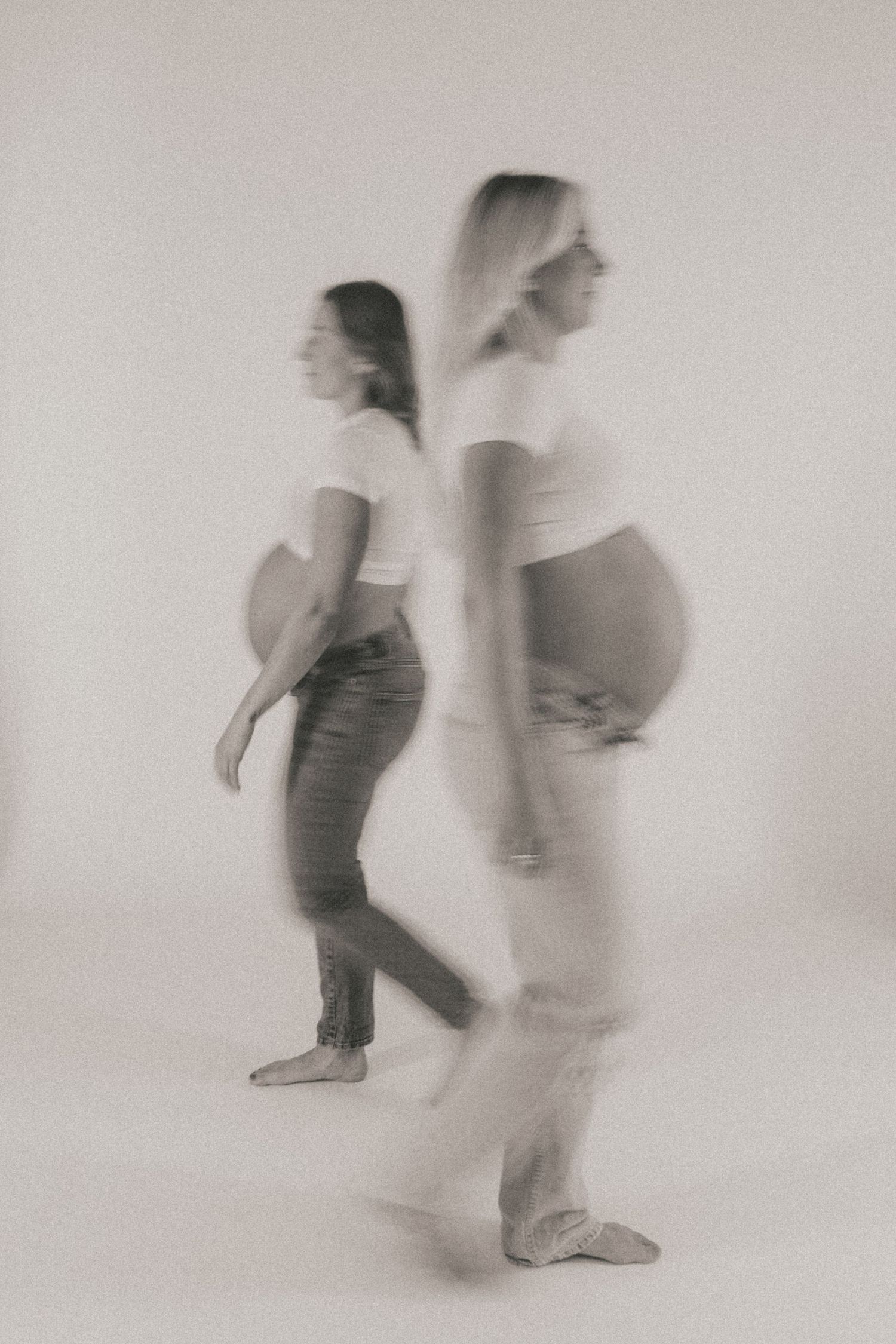 Motion-blur maternity photography showing movement and pregnancy silhouettes in soft focus.