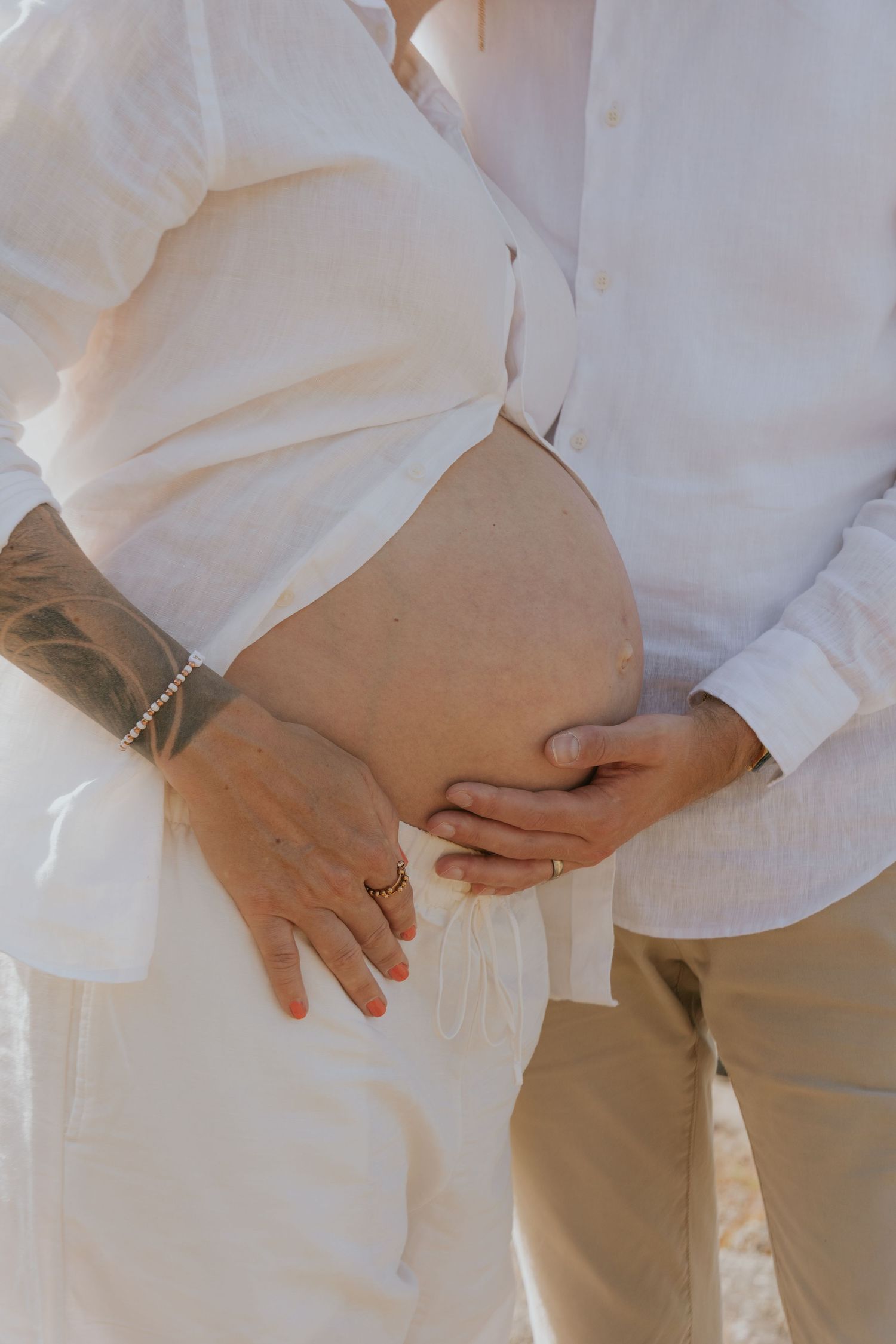 Close-up shots of hands tenderly touching during an intimate moment in white attire.