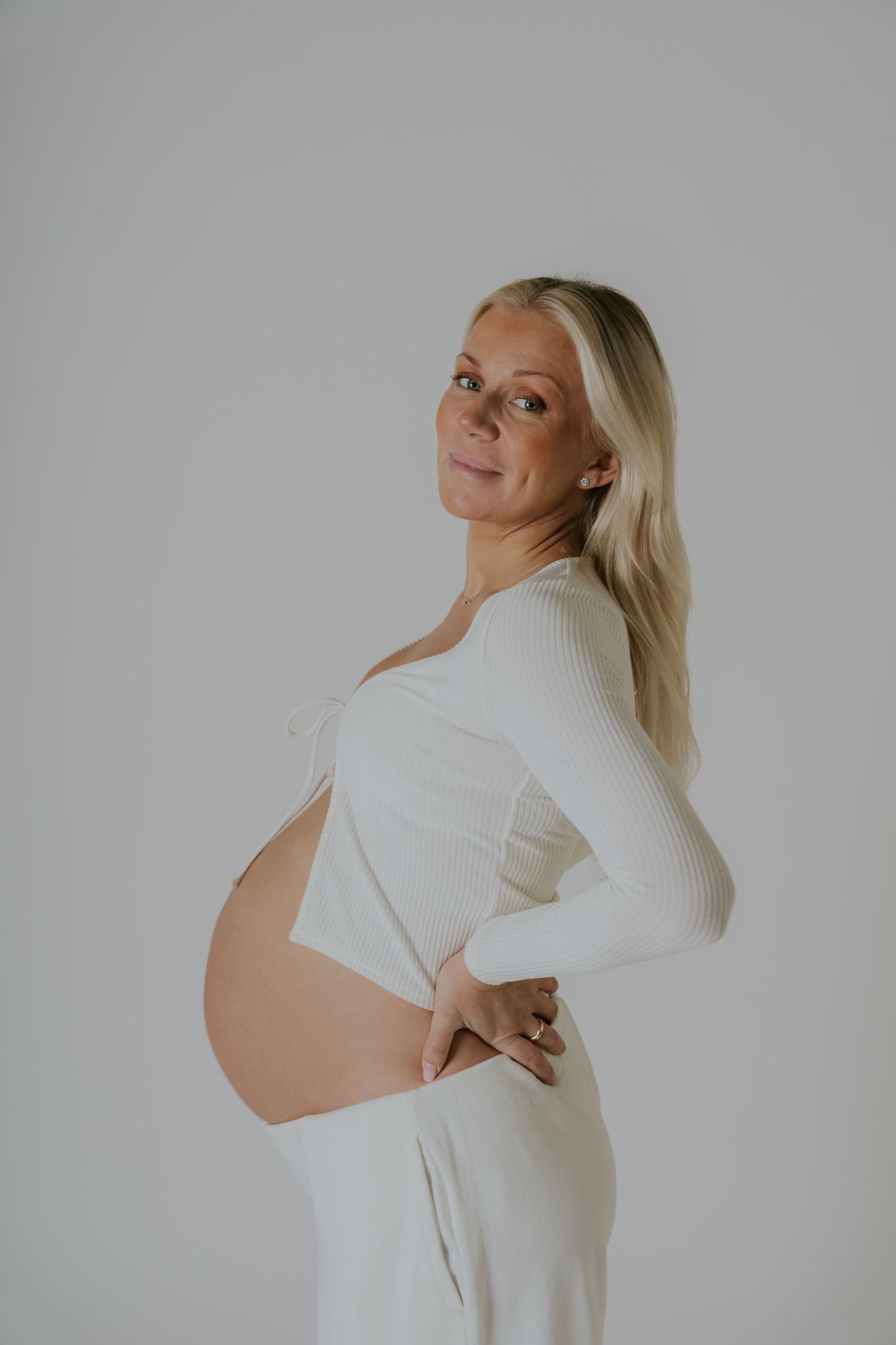 Minimalist maternity portraits in white clothing showing different angles of pregnancy progression.