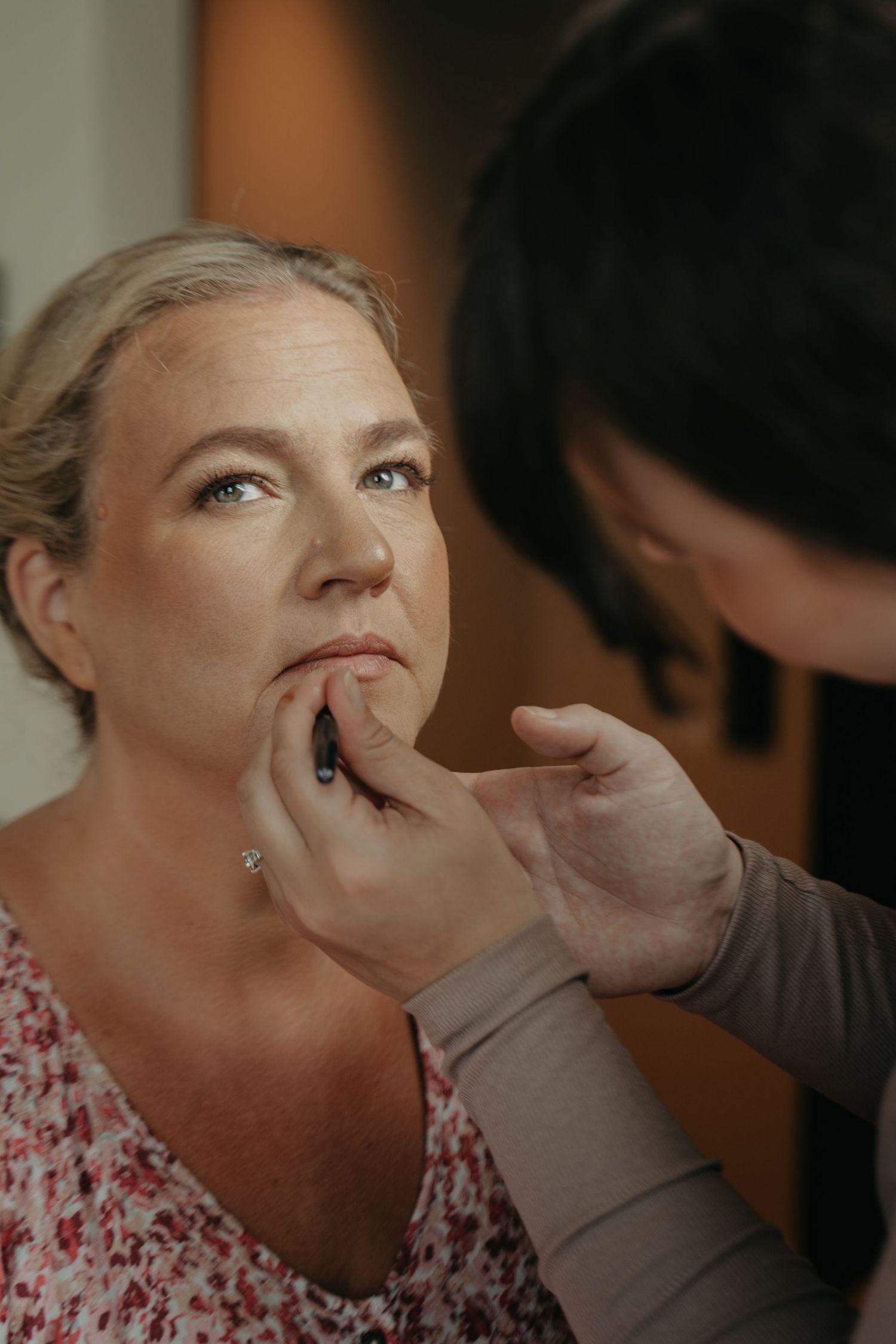 Makeup artist applying lip color during bridal preparation.