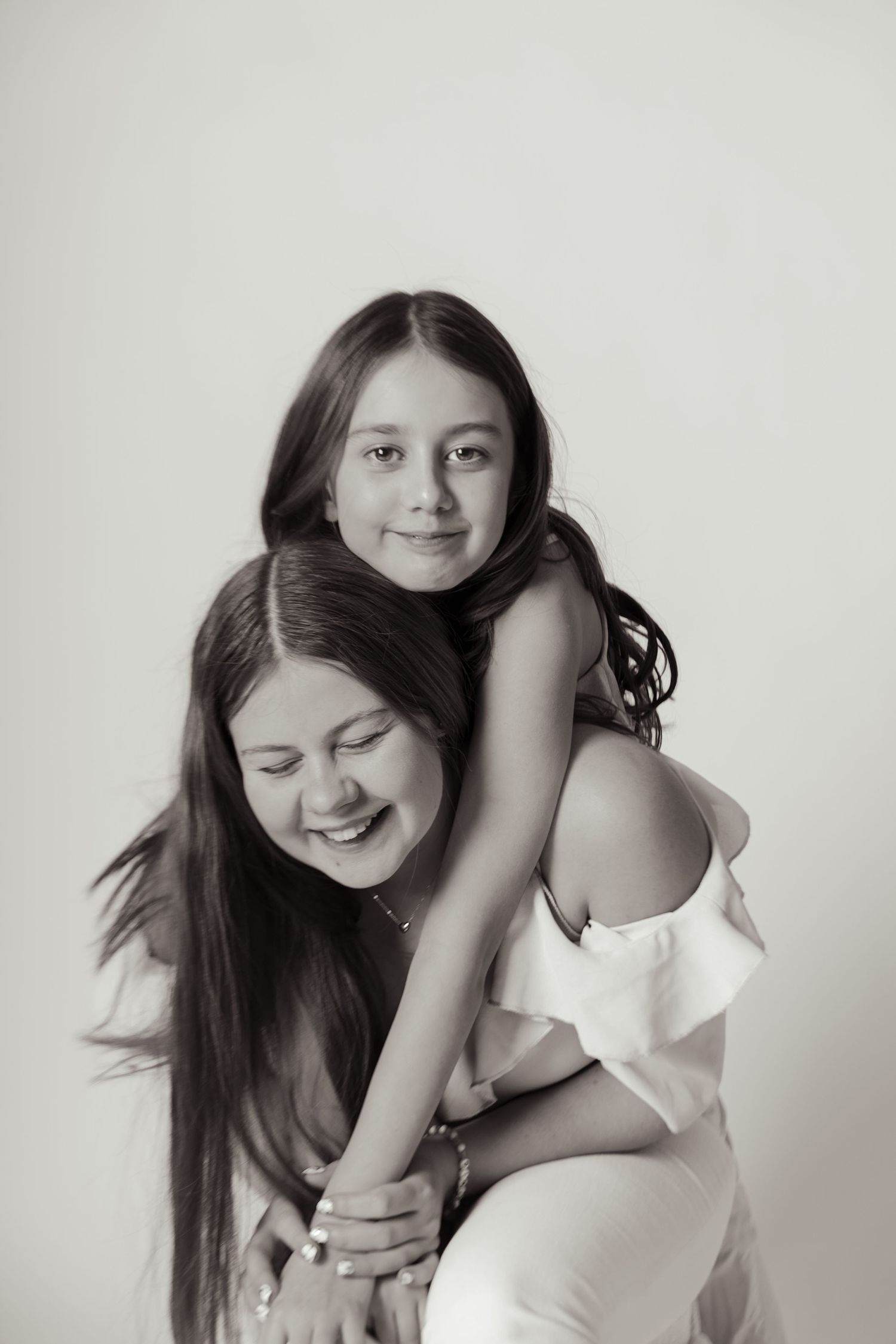 A series of four black and white portraits showing playful interactions between two people in white clothing.