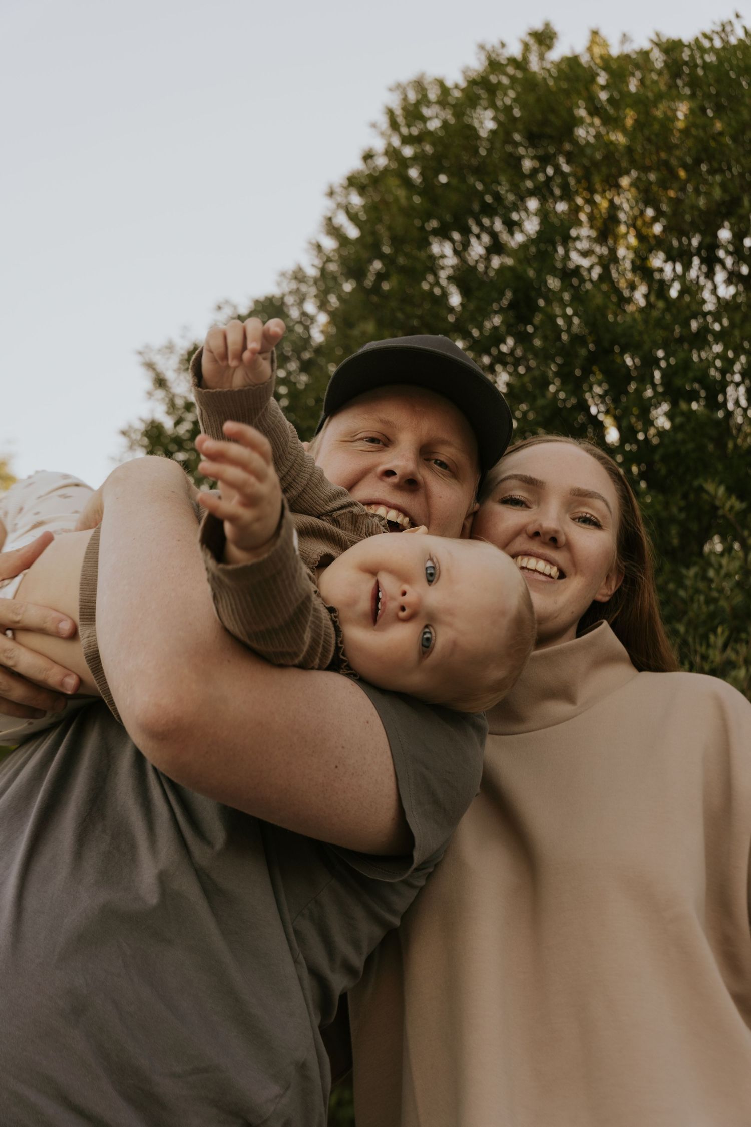 A candid family moment captured outdoors with natural lighting and genuine smiles.