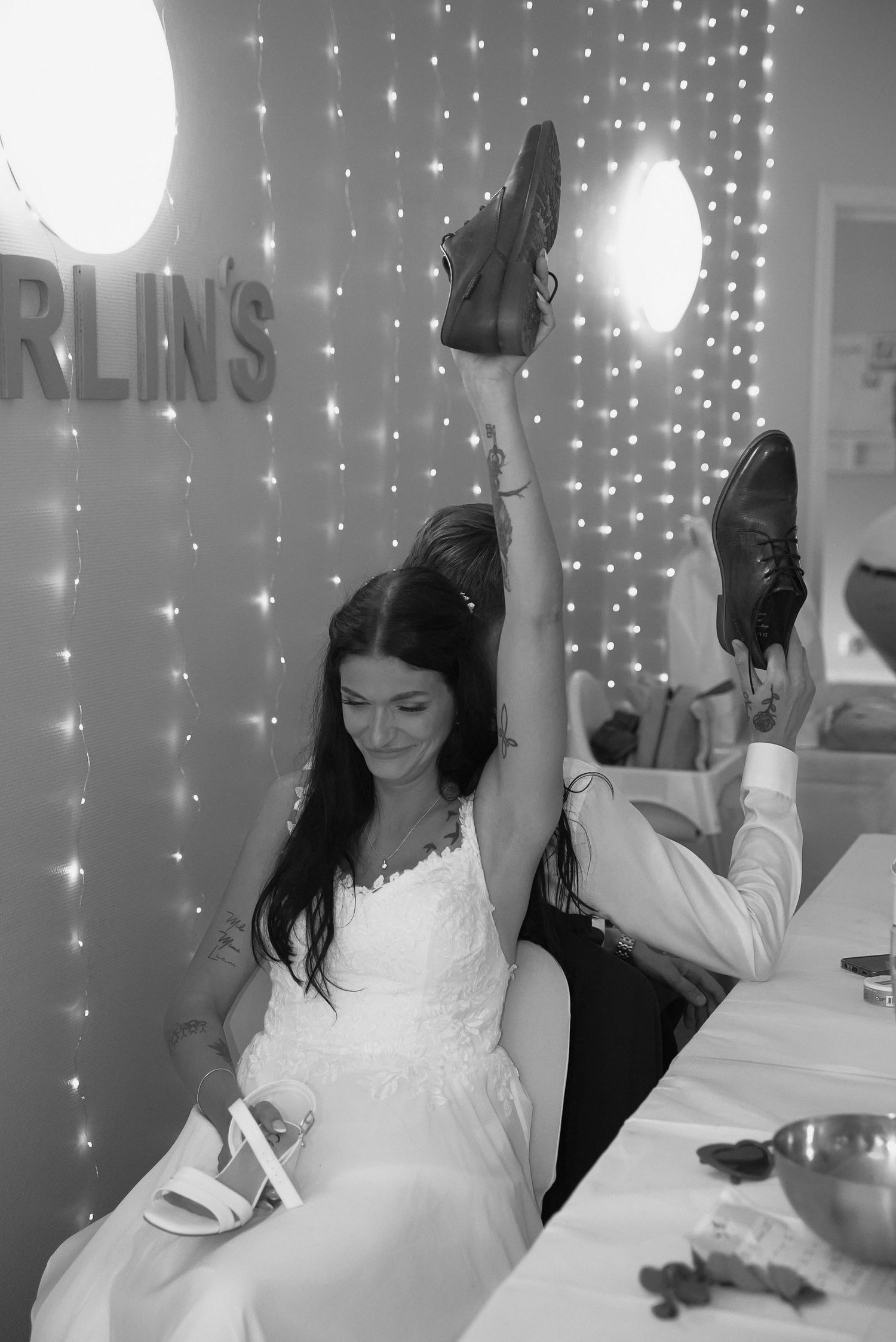A series of black and white photos showing someone in a white dress dancing and celebrating with twinkling lights in background.