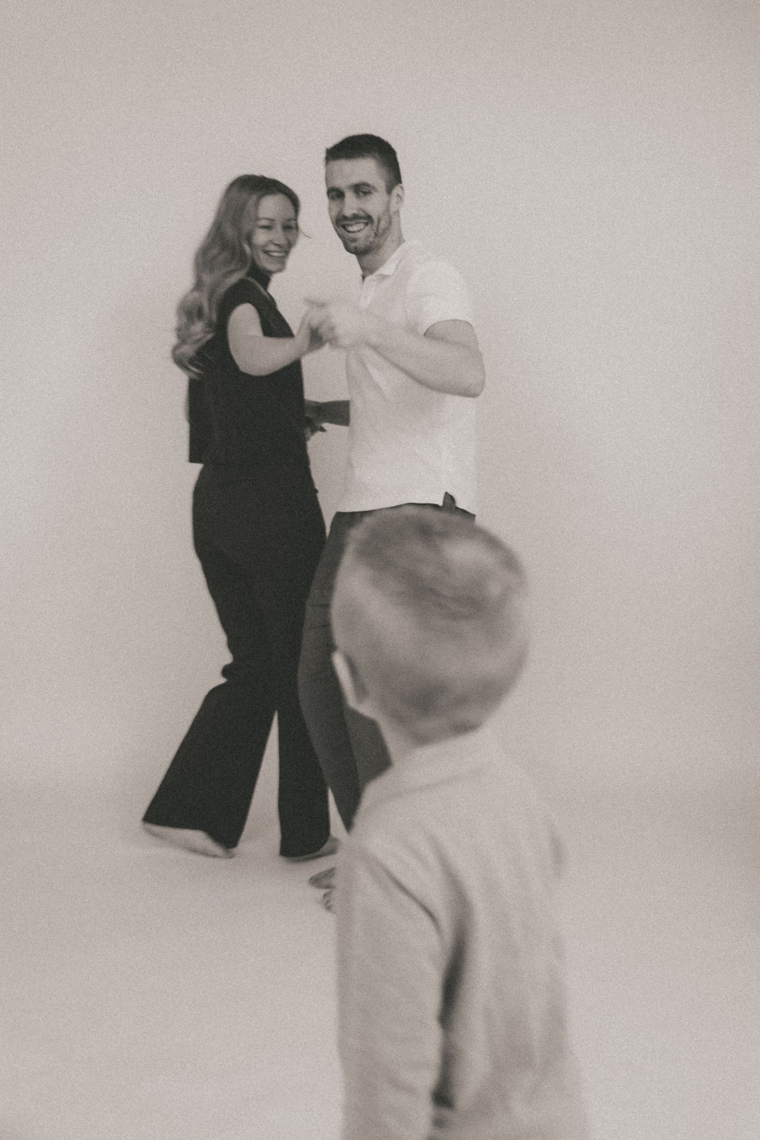 A black and white photo series showing a couple dancing together in a minimalist studio setting.