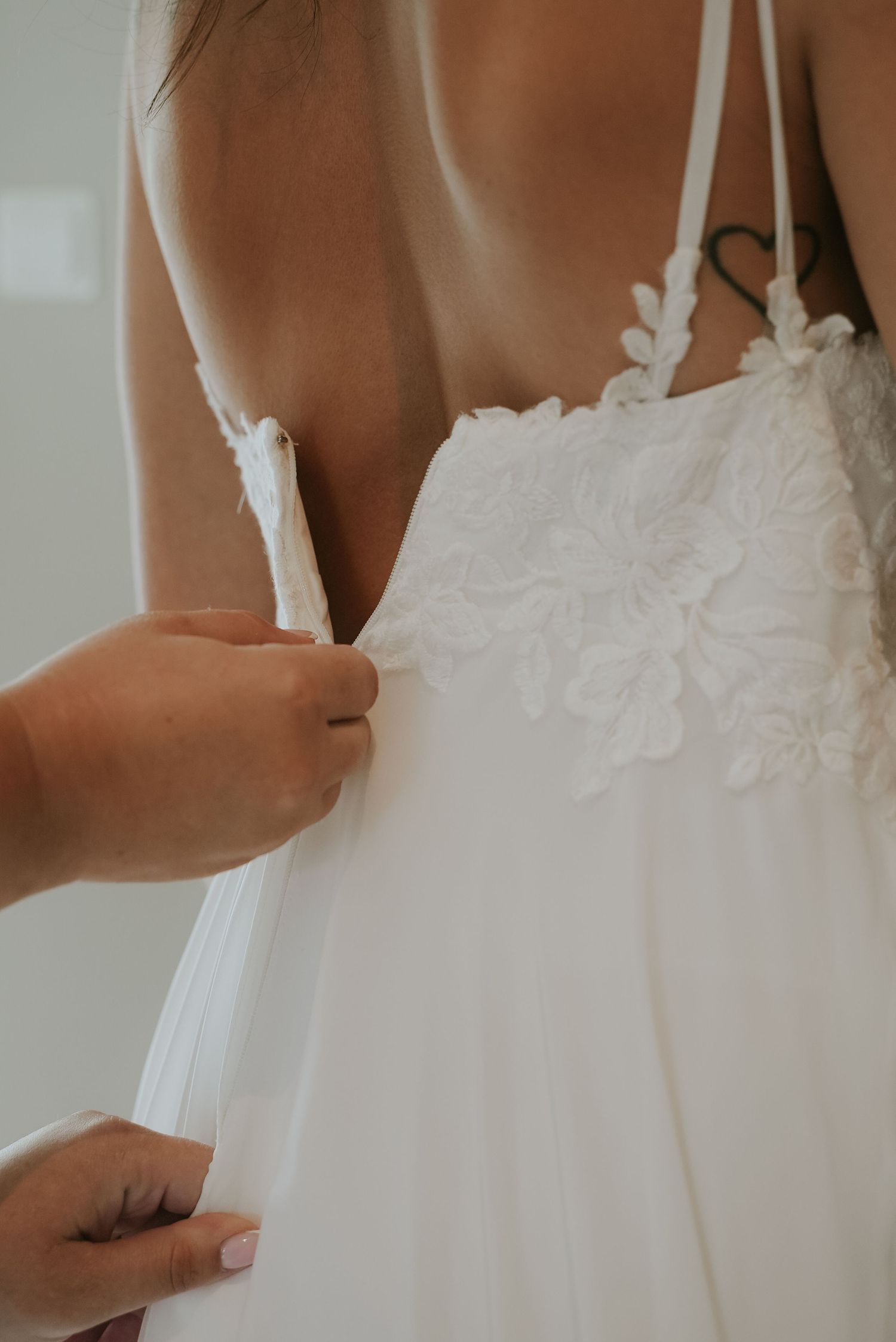 Close-up details of delicate white lace and straps on a wedding dress bodice.