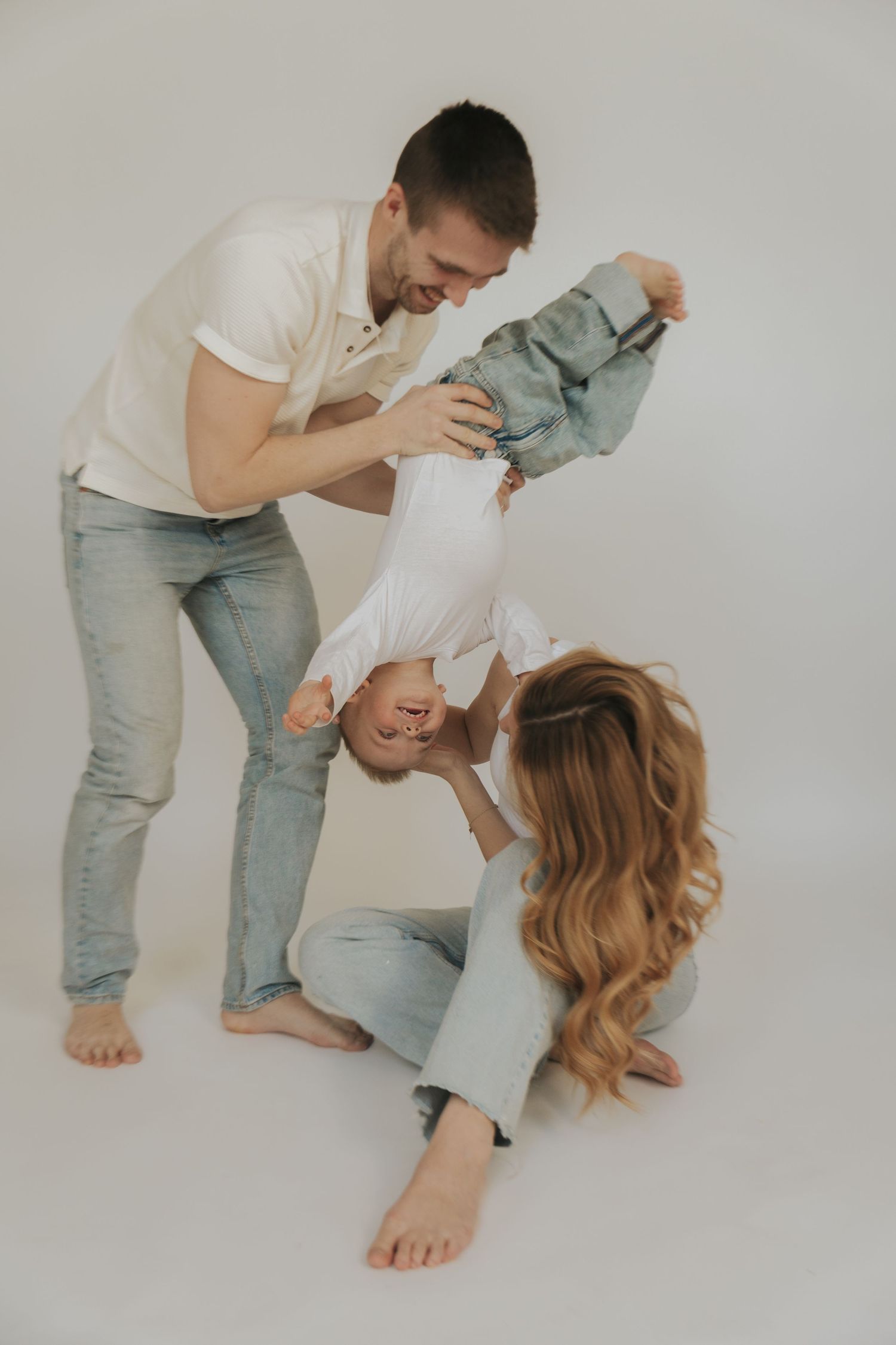 Playful family moment captured against white background as they share laughter and fun together.
