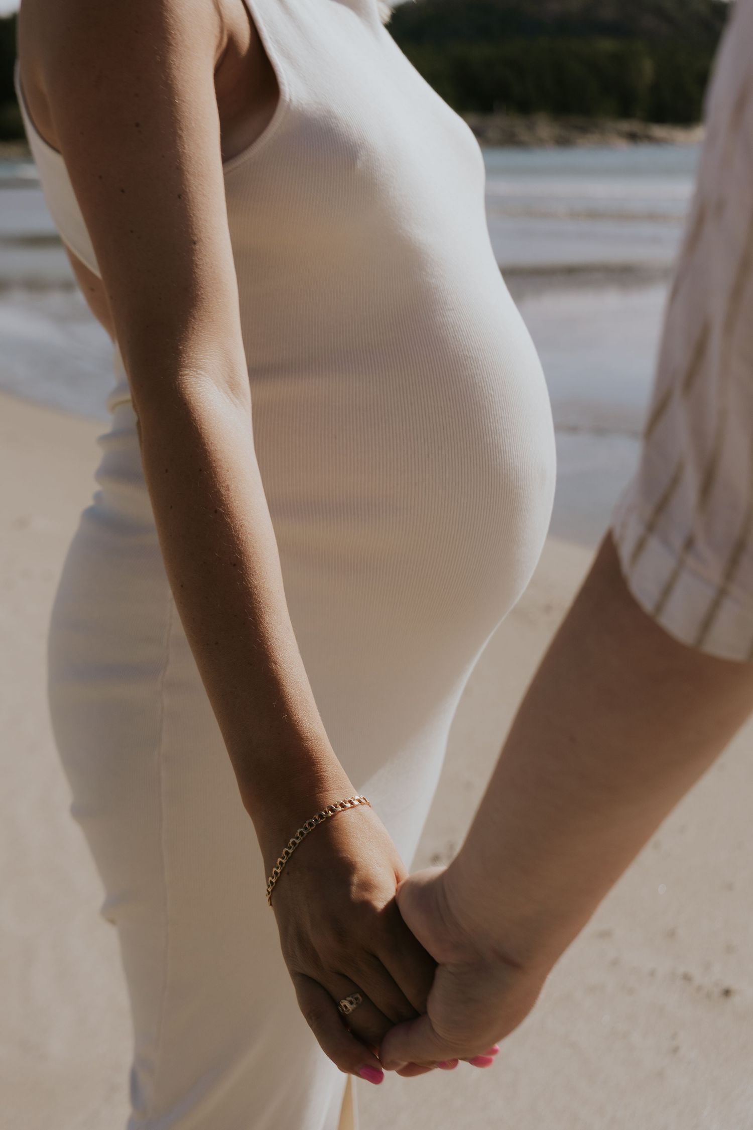 Close-up series showing pregnant belly in white dress from different angles.