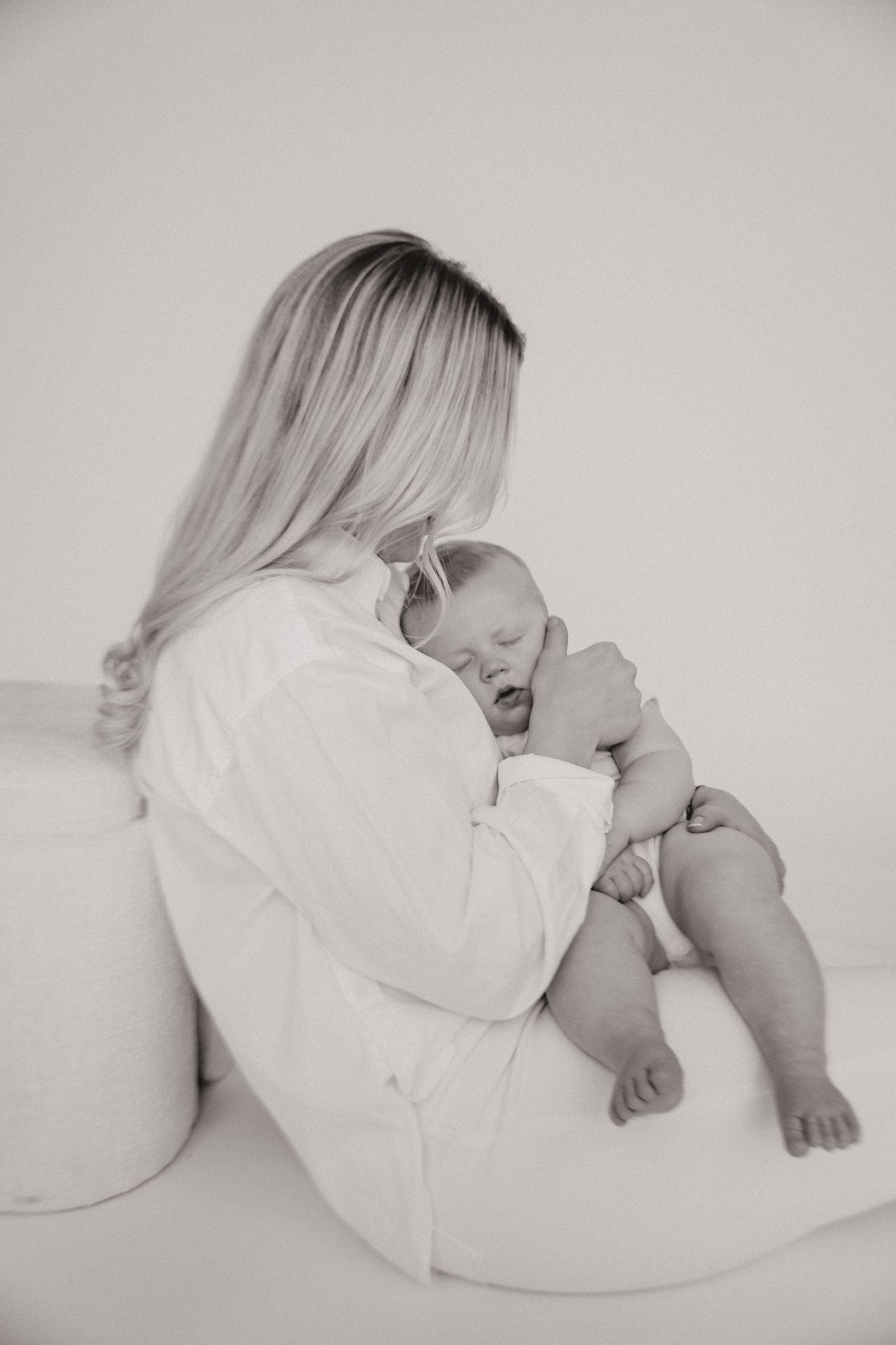 Black and white image of parent cradling sleeping infant on white background.