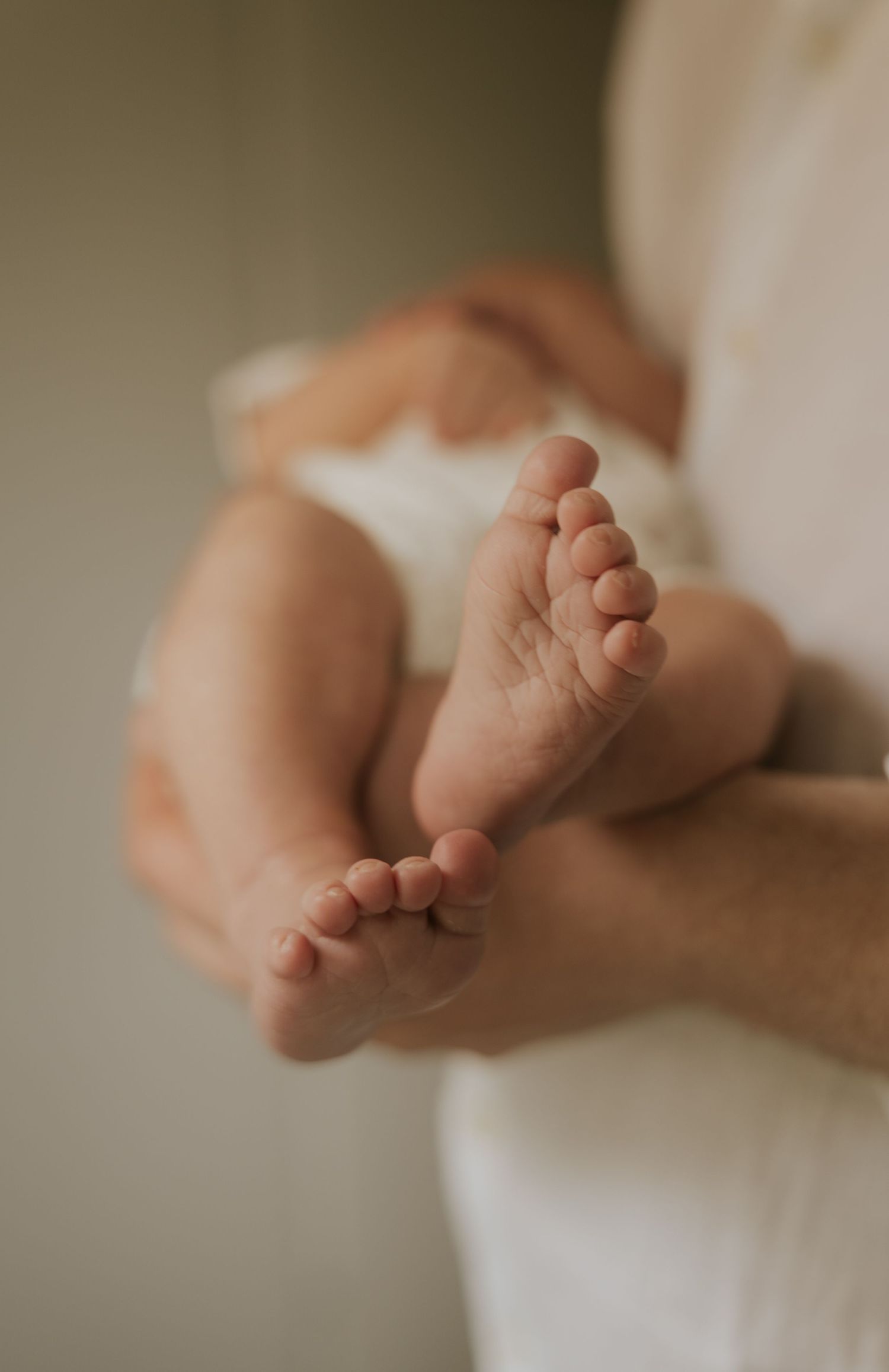 A series of close-up photos showing tiny baby feet wrapped in soft white fabric, creating a gentle and tender sequence.