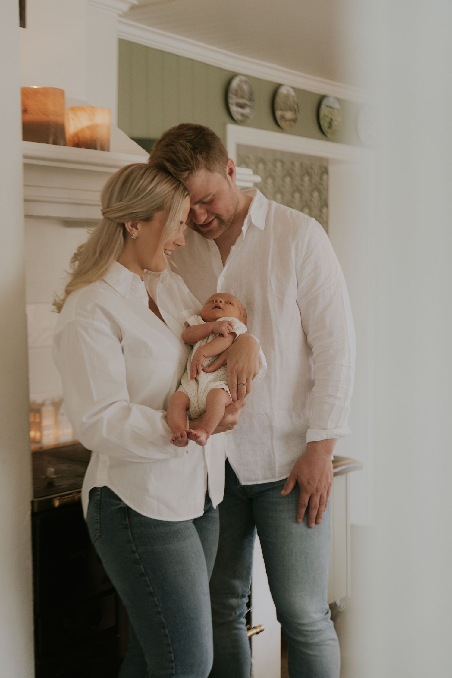 A couple in white shirts and jeans share tender moments in a bright interior space.