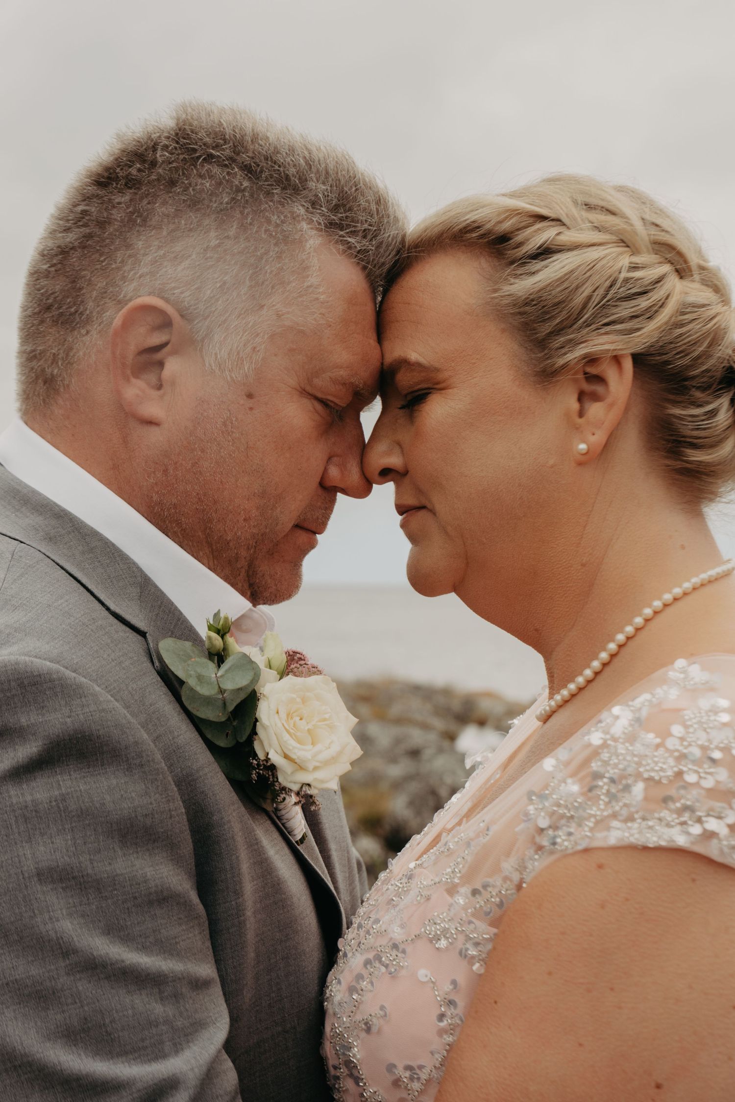 Tender close-up portrait of newlyweds in soft gray tones.