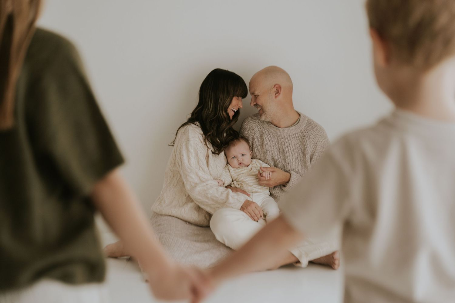 A tender family moment captured in soft muted tones as parents cradle their newborn baby at home.