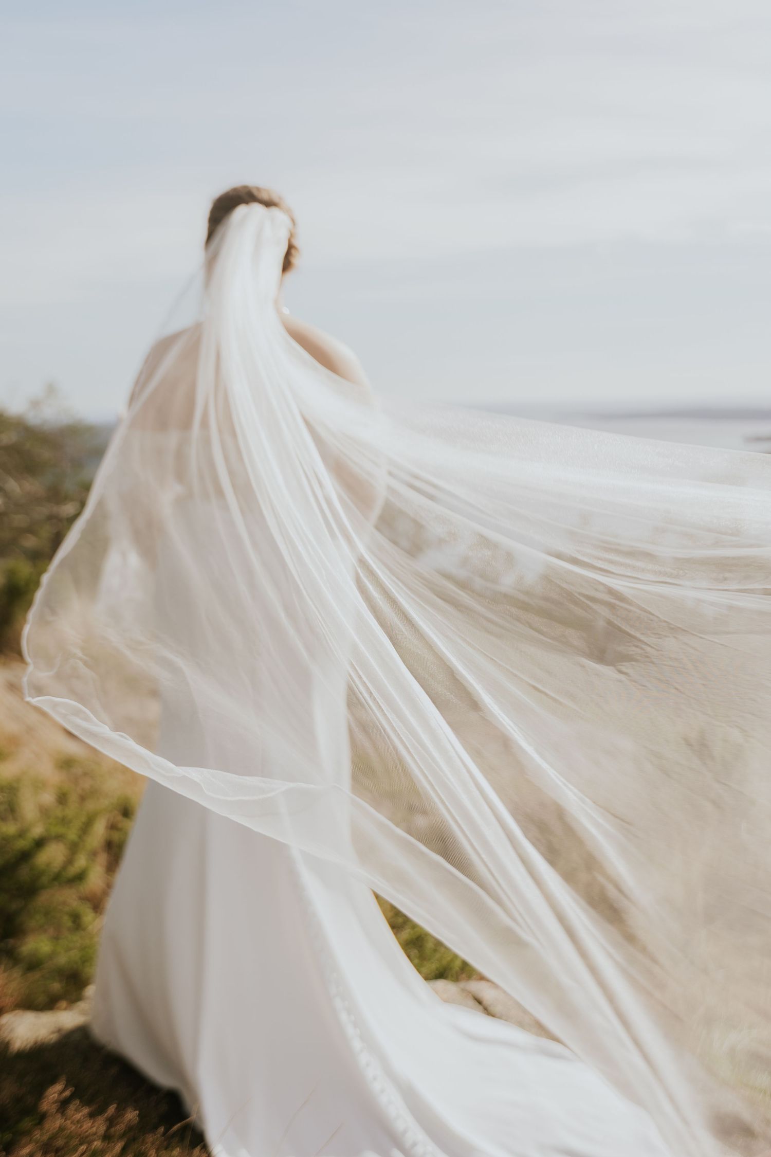 Ethereal bridal veil flowing in the wind against a scenic landscape.