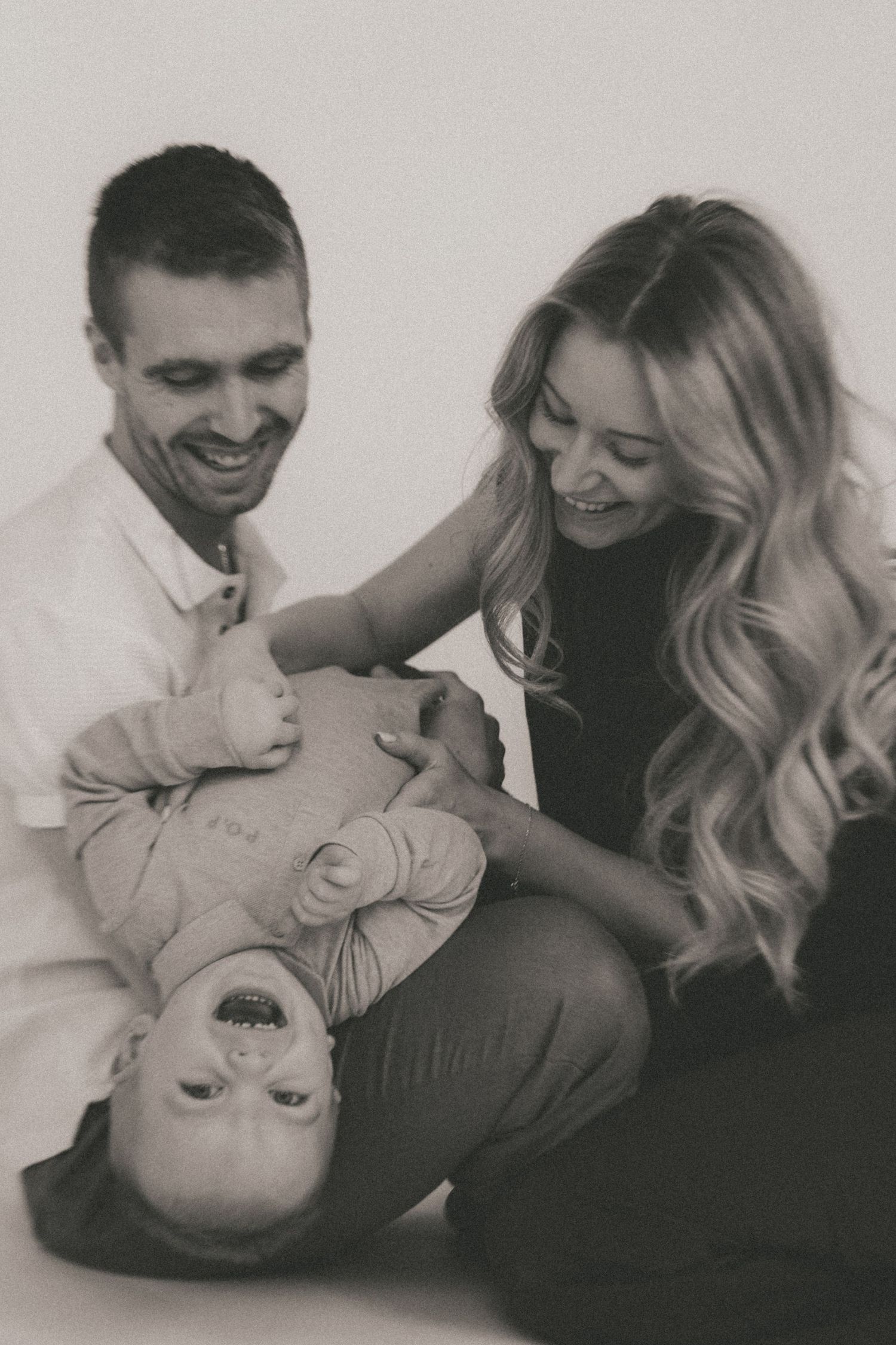 Black and white candid photo sequence capturing intimate moments between a couple and their baby.