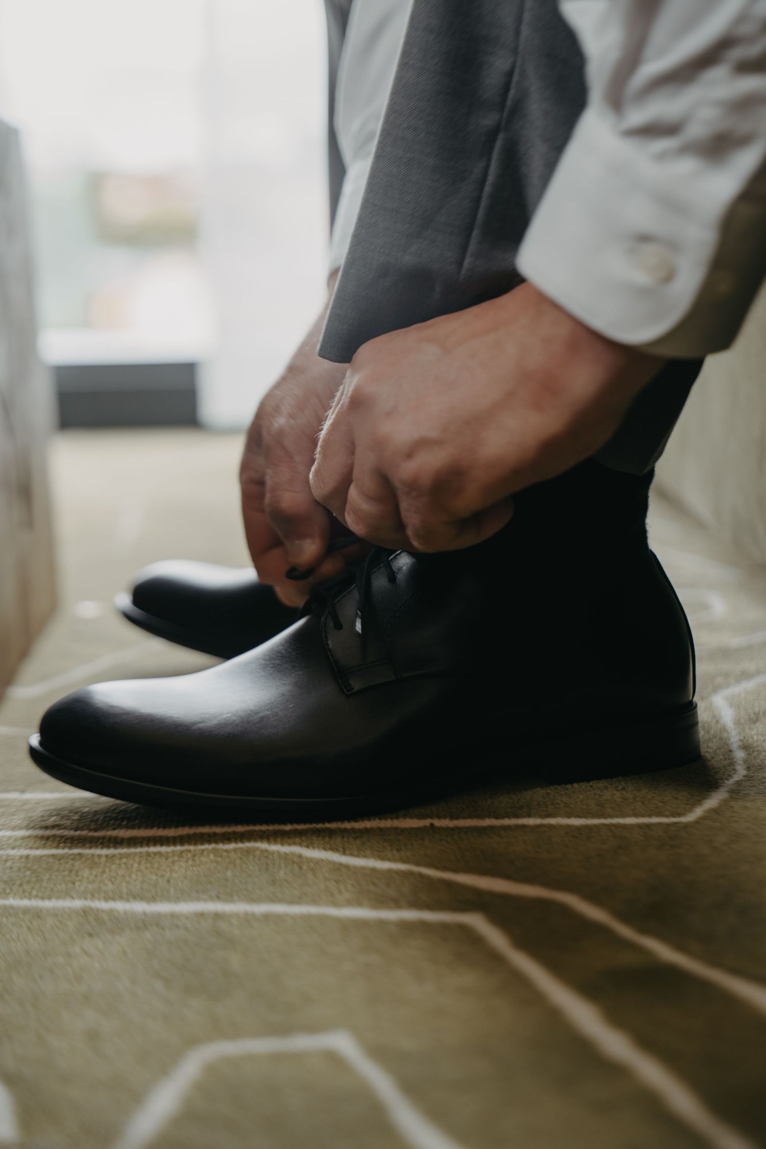 Close-up of hands lacing up formal black leather dress shoes.
