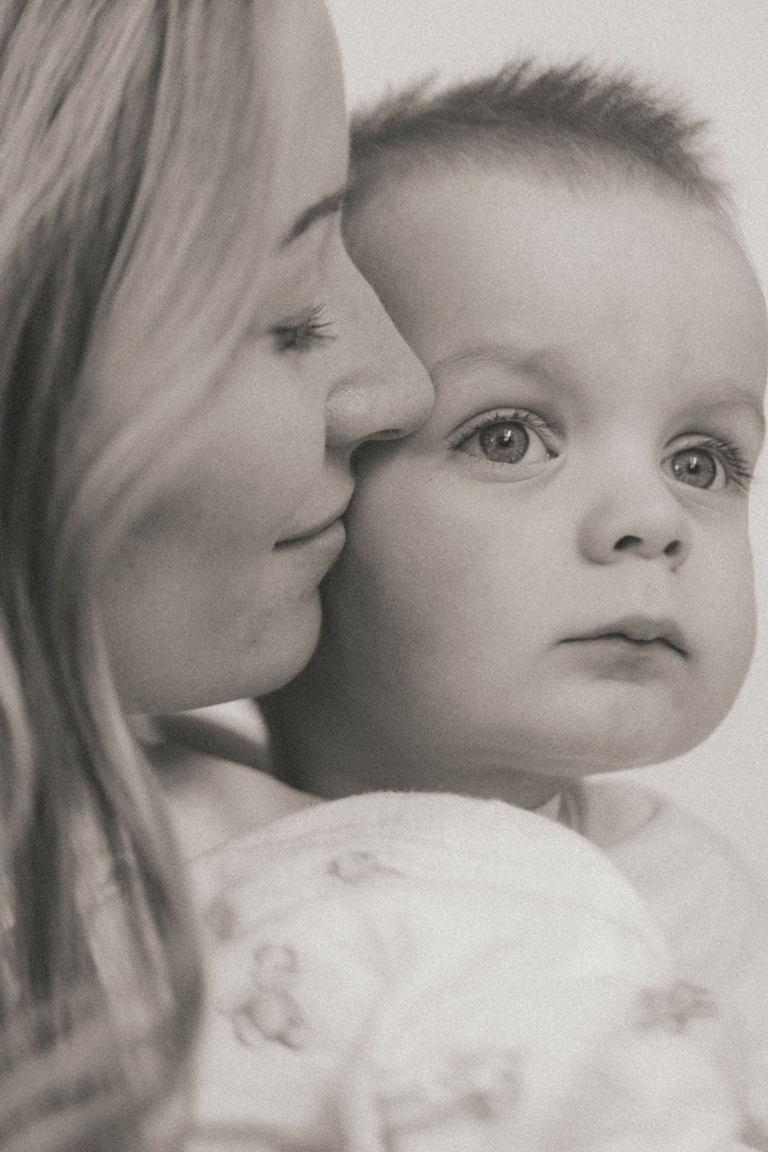 A series of black and white portraits showing tender moments between parent and baby in soft lighting.