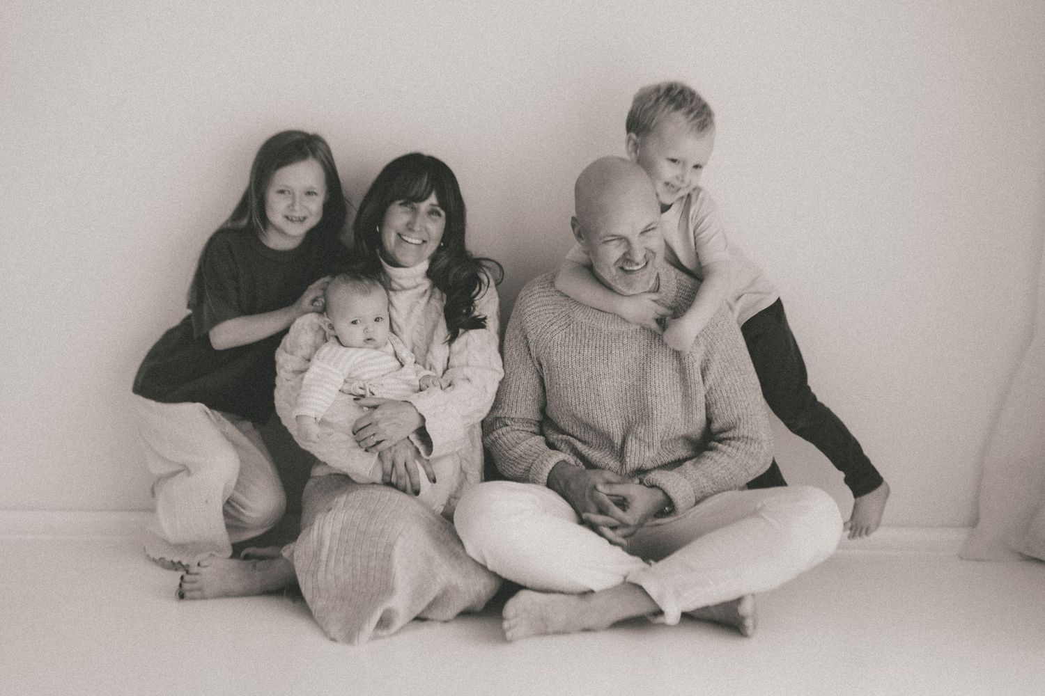 A series of black and white family photographs showing intimate moments between parents and children on a white background.