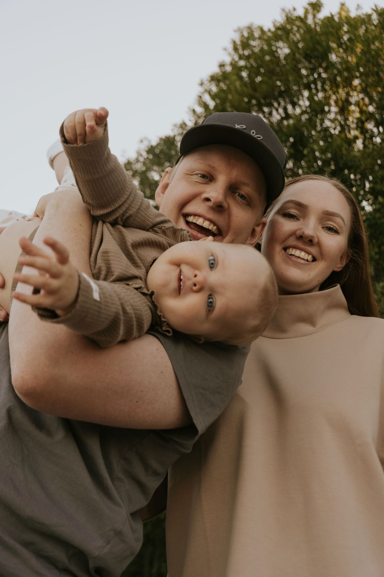 A joyful family portrait showing playful expressions and warm embraces outdoors against a natural backdrop.