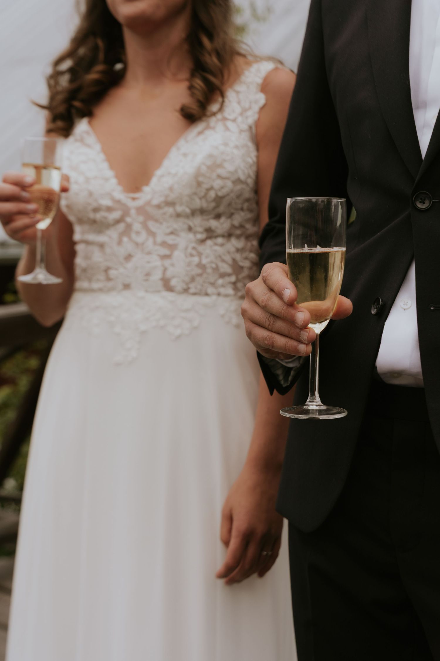 Wedding guests hold champagne glasses while wearing formal attire at an elegant celebration.