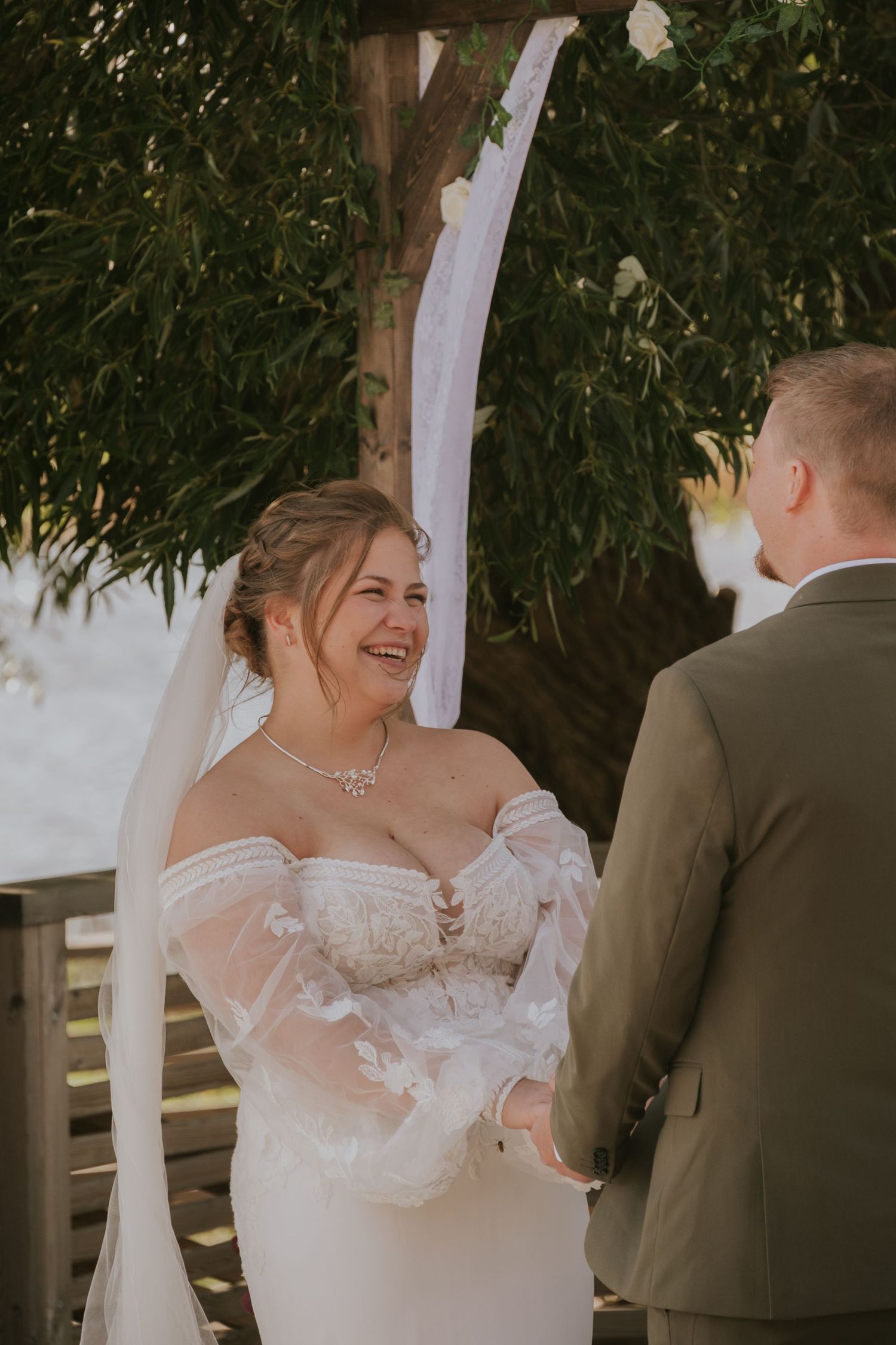 Wedding couple sharing intimate moment under draped fabric canopy during outdoor ceremony.
