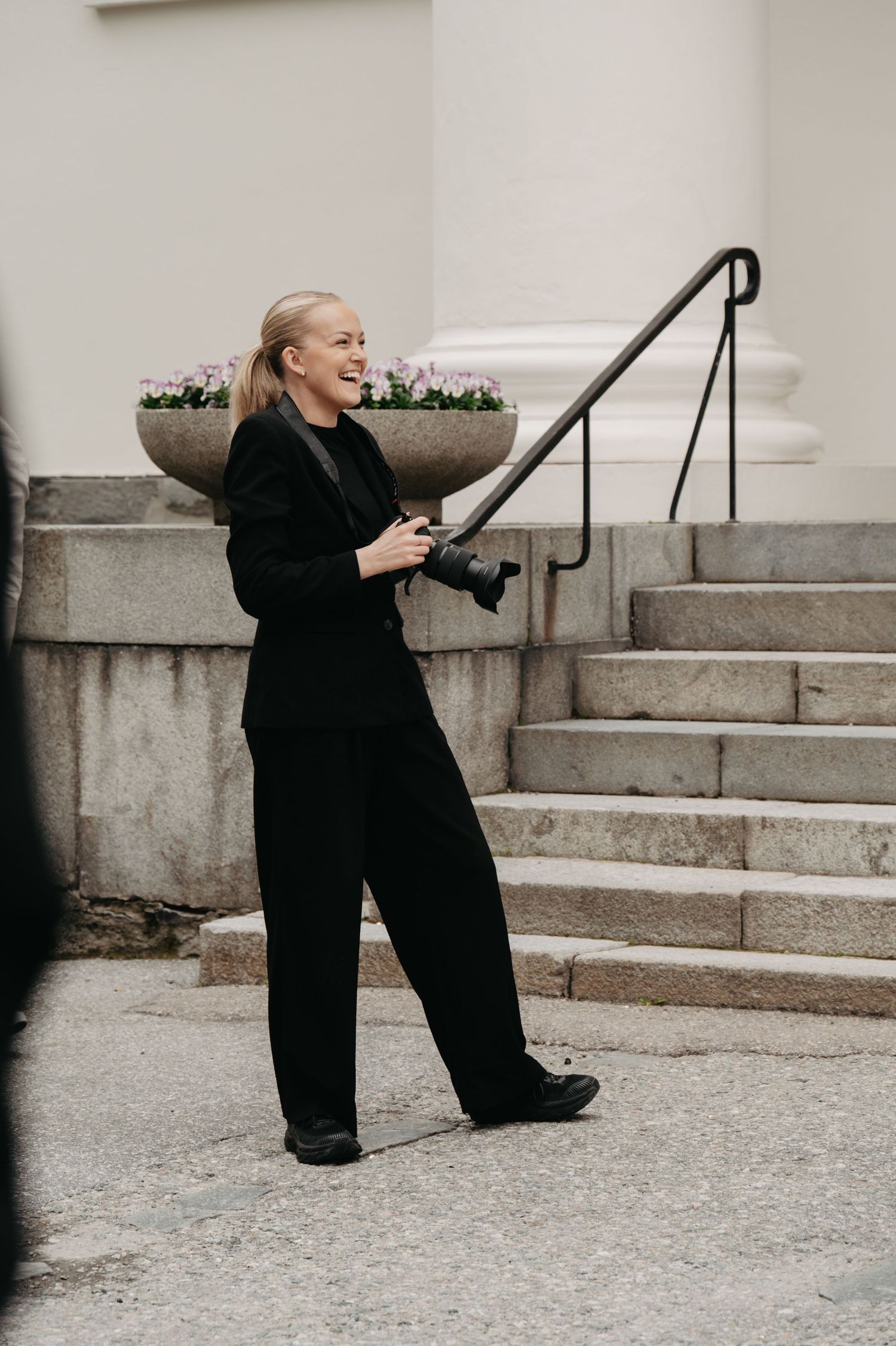 Person in black outfit sitting playfully on concrete steps in artistic poses.