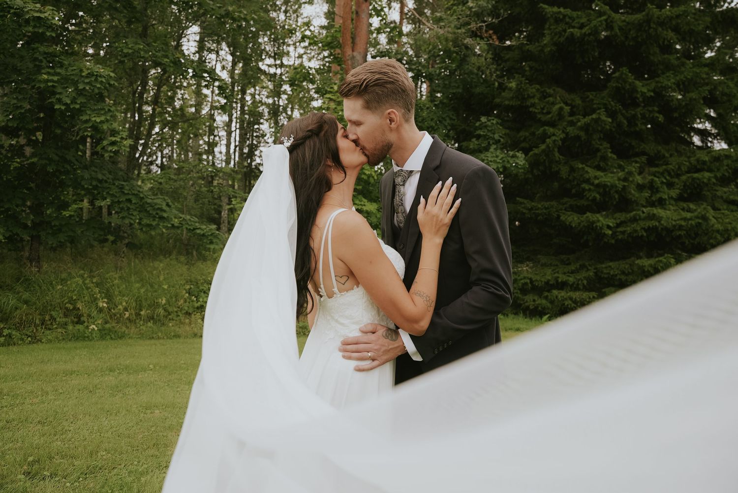 Romantic outdoor wedding portraits with a flowing veil against a natural backdrop.