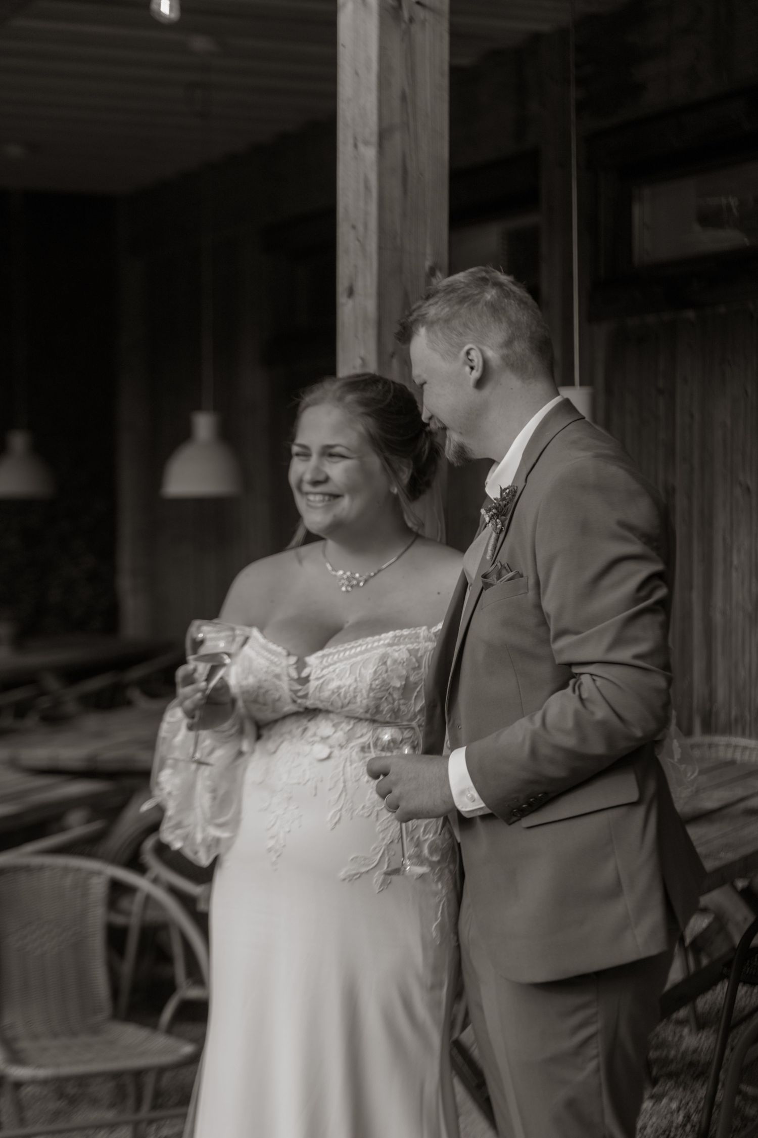 A couple in wedding attire share an intimate moment in black and white photography.