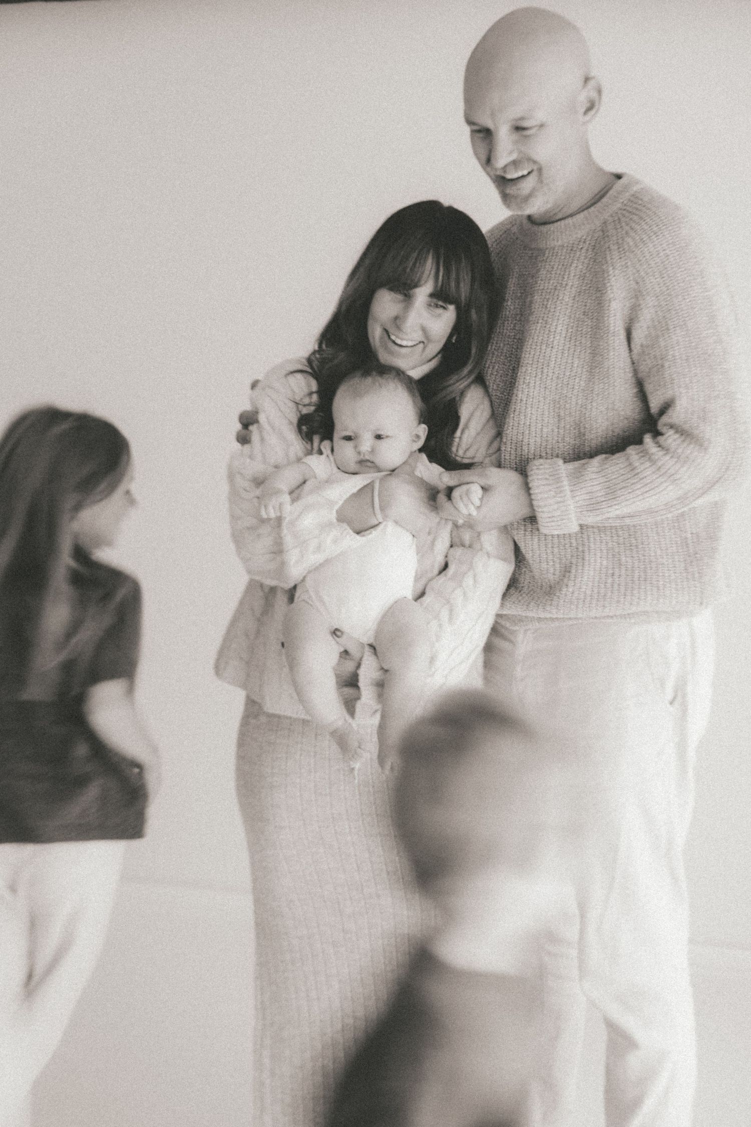 Candid family photography showing joyful moments in minimalist white studio setting.