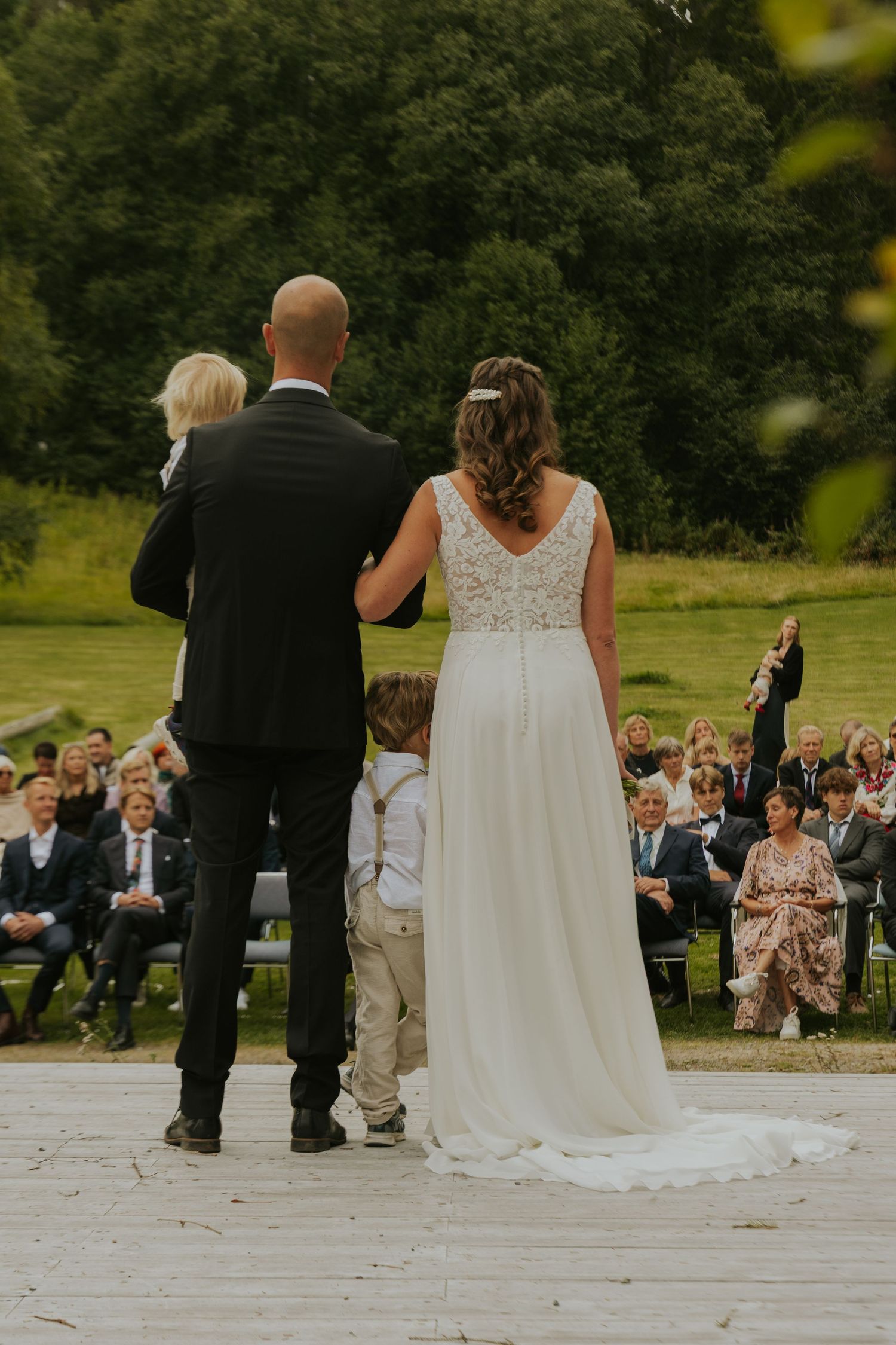 Wedding ceremony on a deck with guests seated in the background.