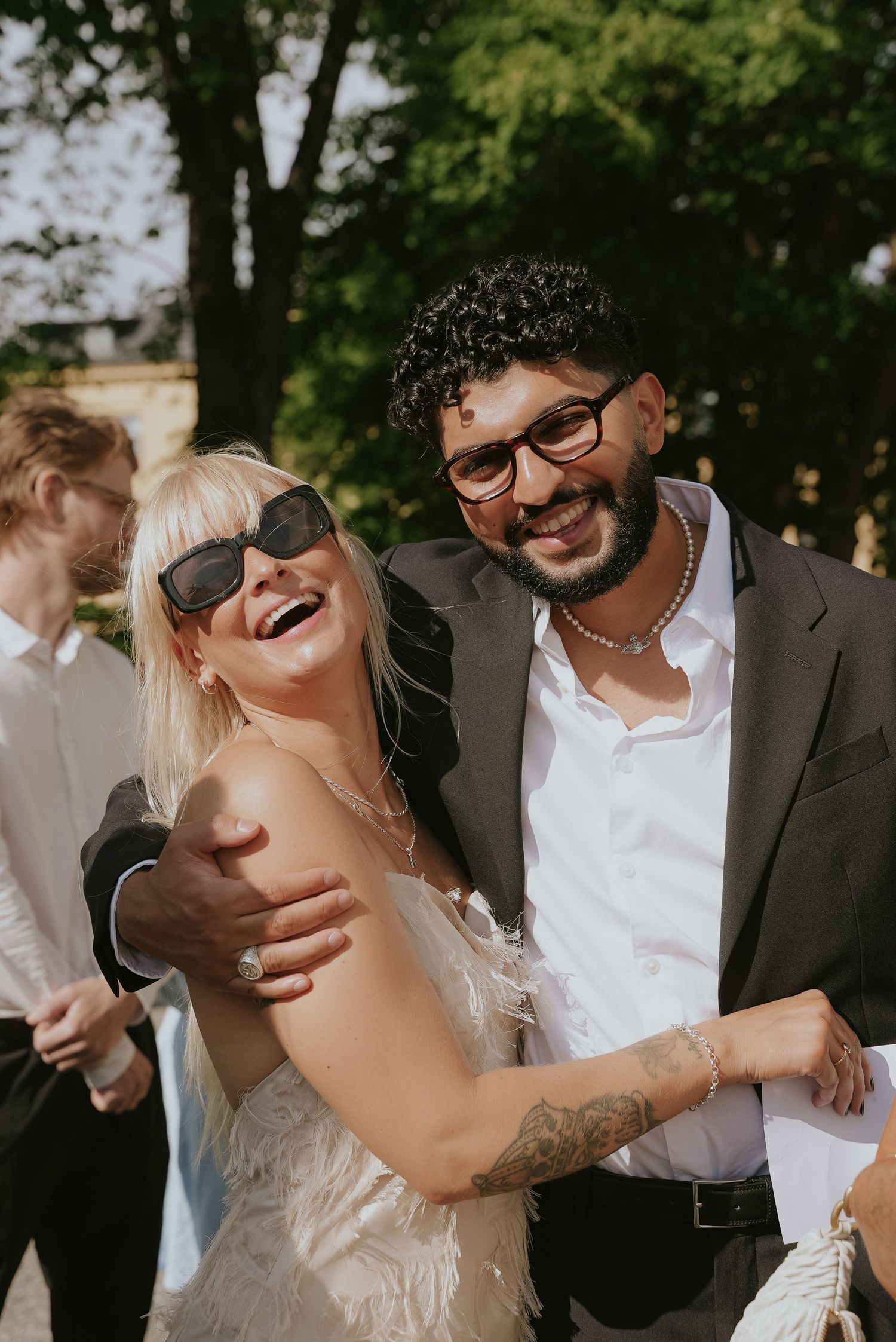 A joyful couple shares candid laughing moments together outdoors during their wedding celebration.