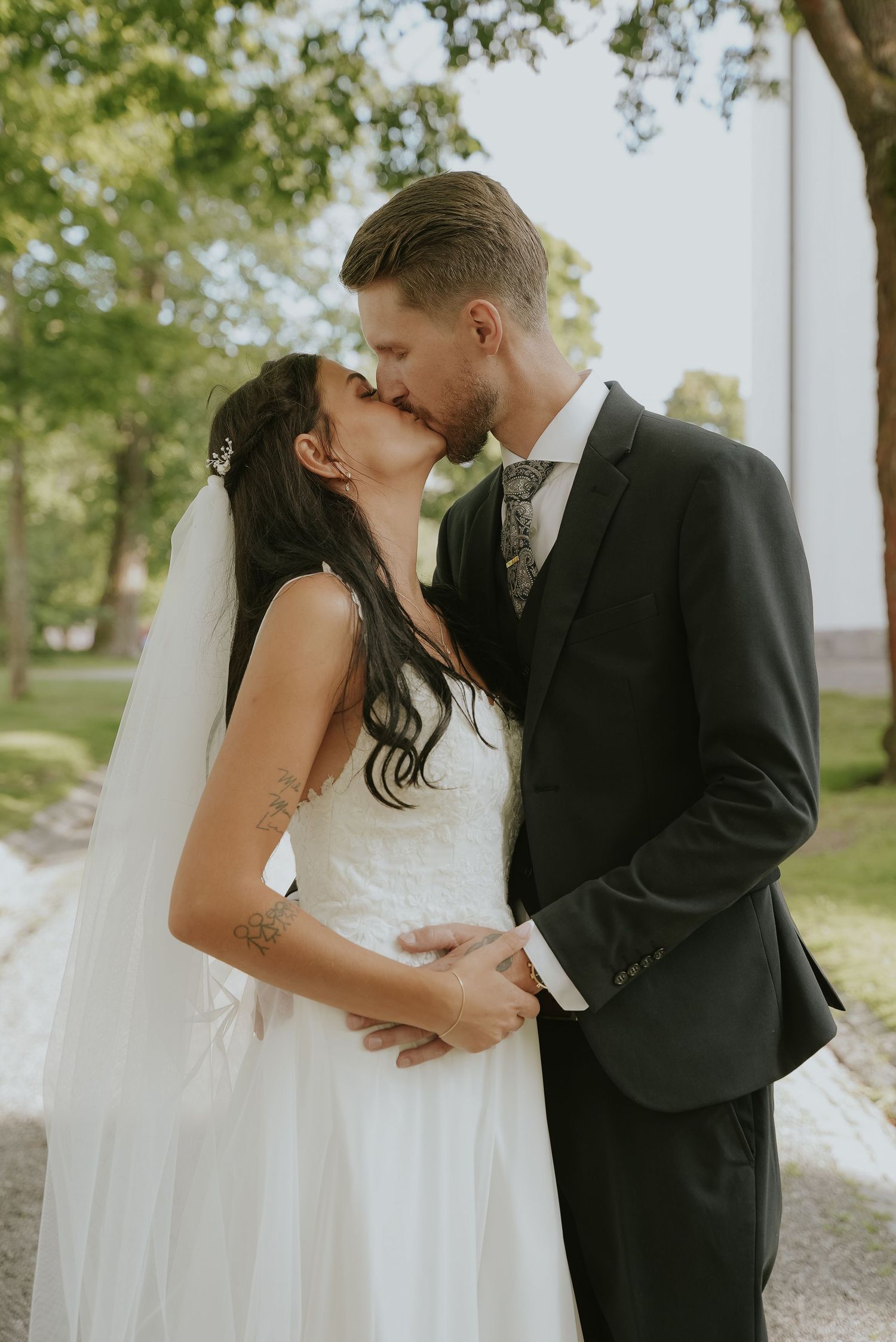 A romantic wedding couple shares intimate kisses in a series of tender outdoor portraits on their special day.