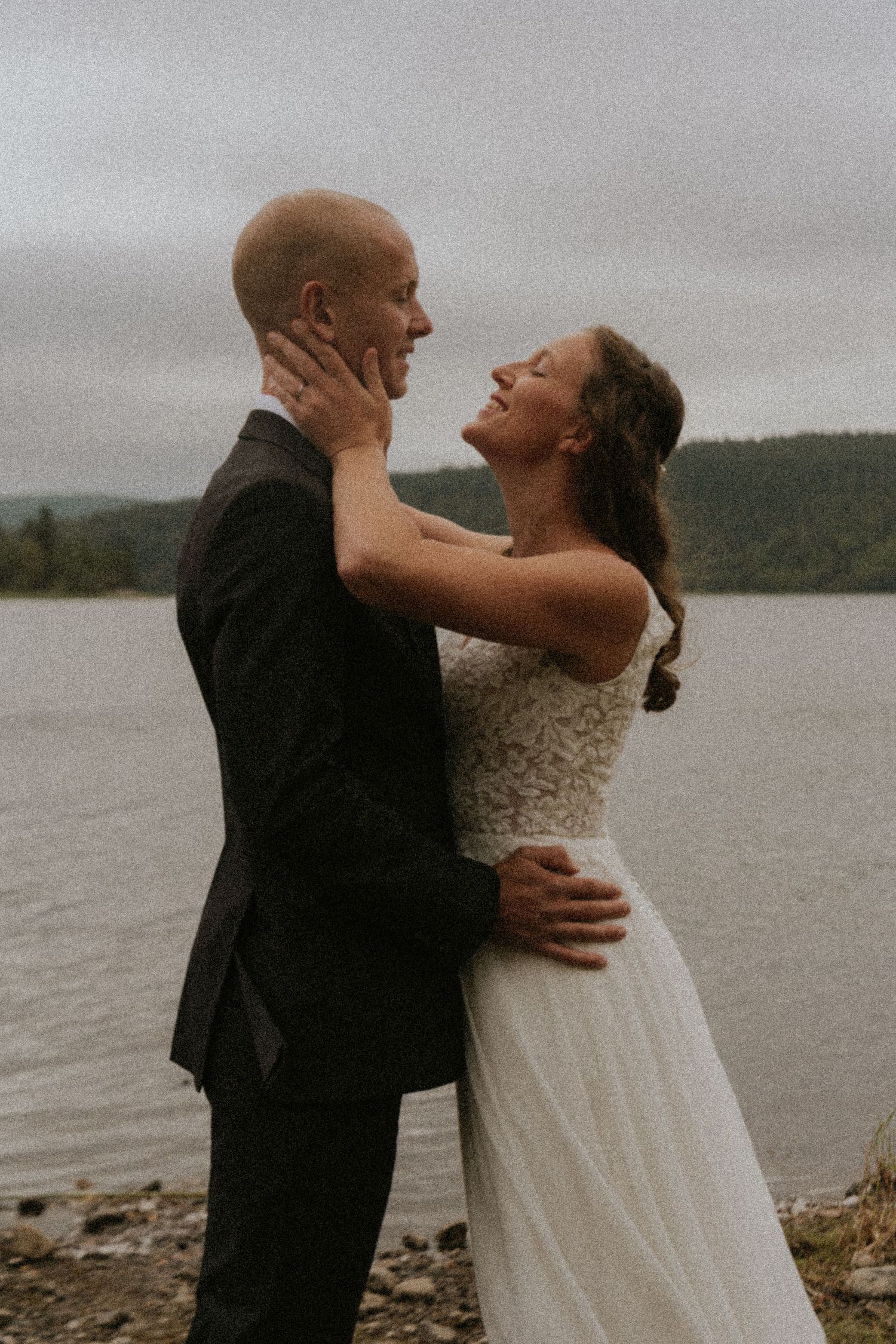 Intimate moment between newlyweds sharing tender embrace by water.