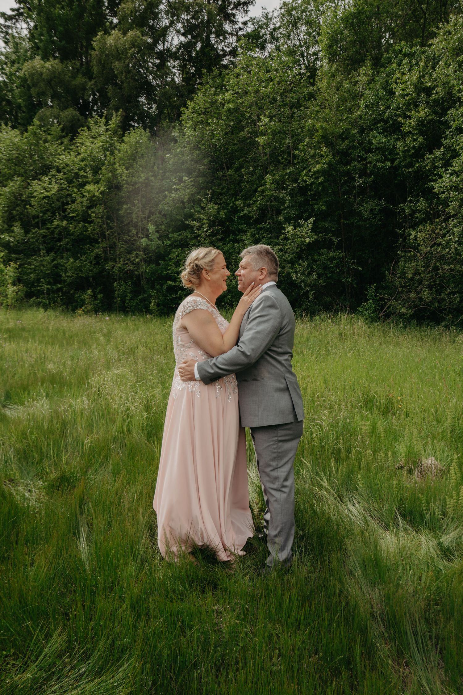 Romantic wedding portrait in tall grass meadow with natural green backdrop.