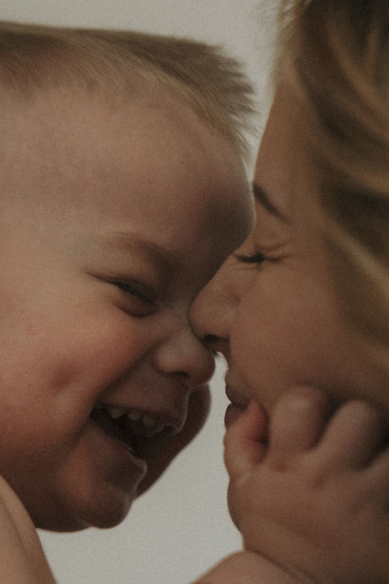 A tender moment of joy and laughter shared between parent and child touching noses in warm lighting.