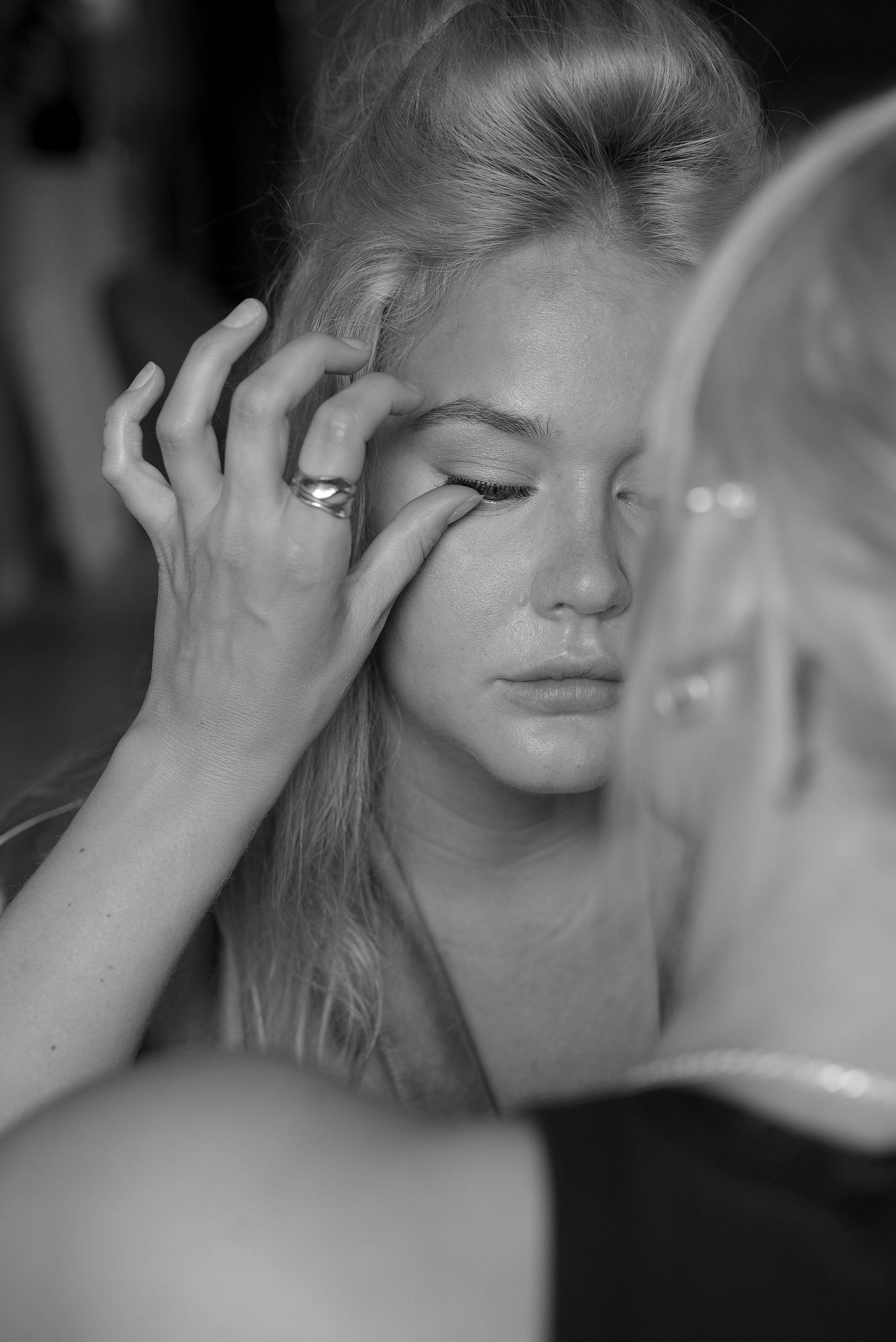 Black and white portrait of a woman touching her face with closed eyes in a reflective, intimate moment.