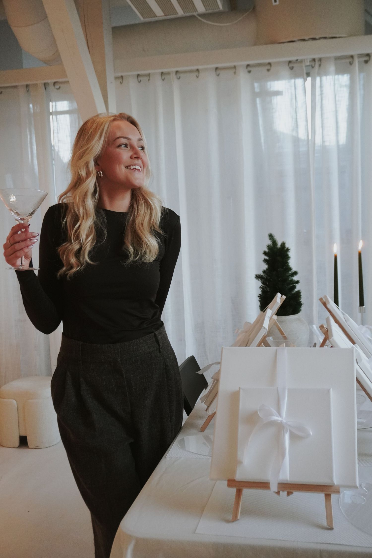 Person in black sweater dances and moves gracefully through bright white interior space with curtains and modern decor.