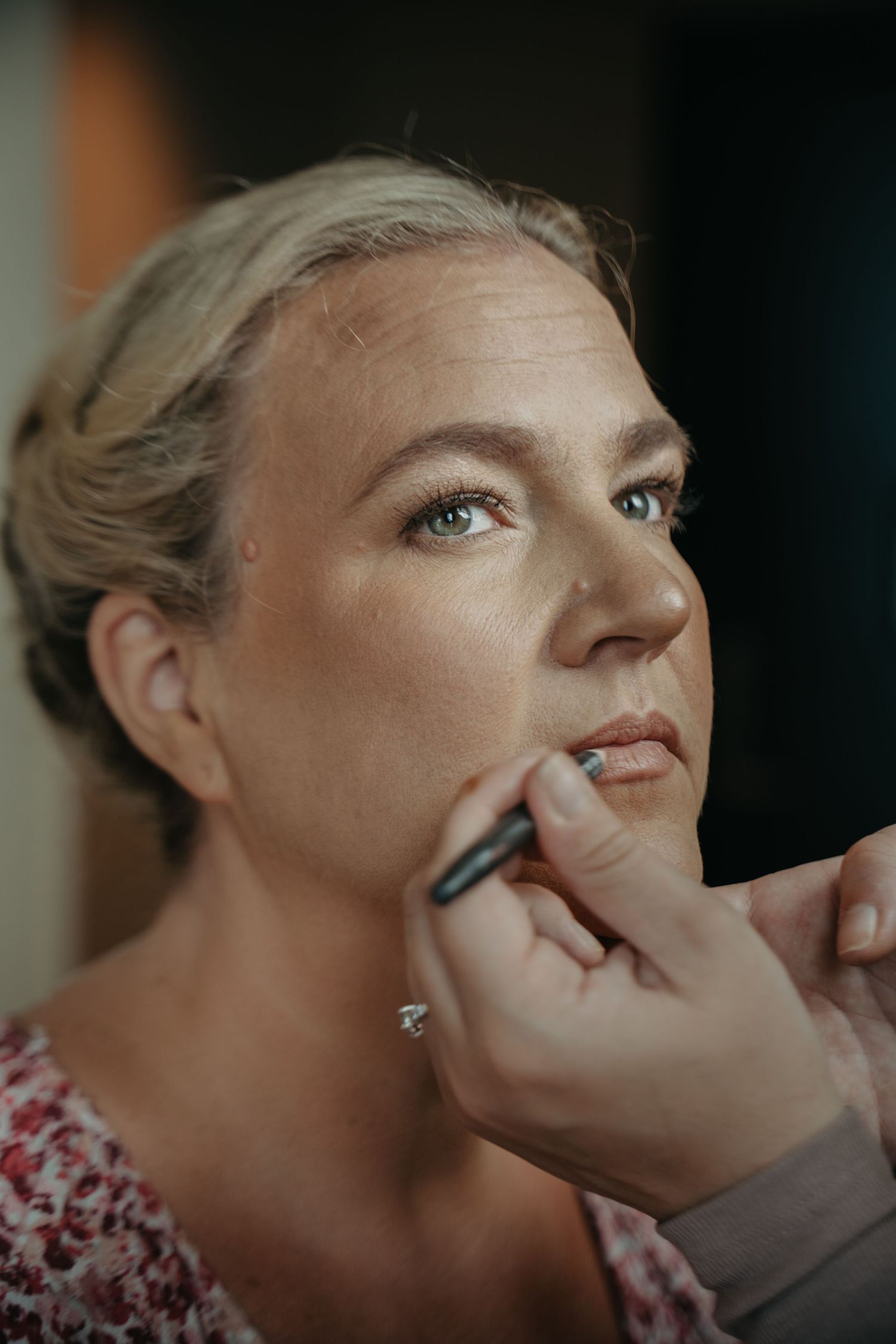 Makeup artist applying lipstick during bridal preparation.