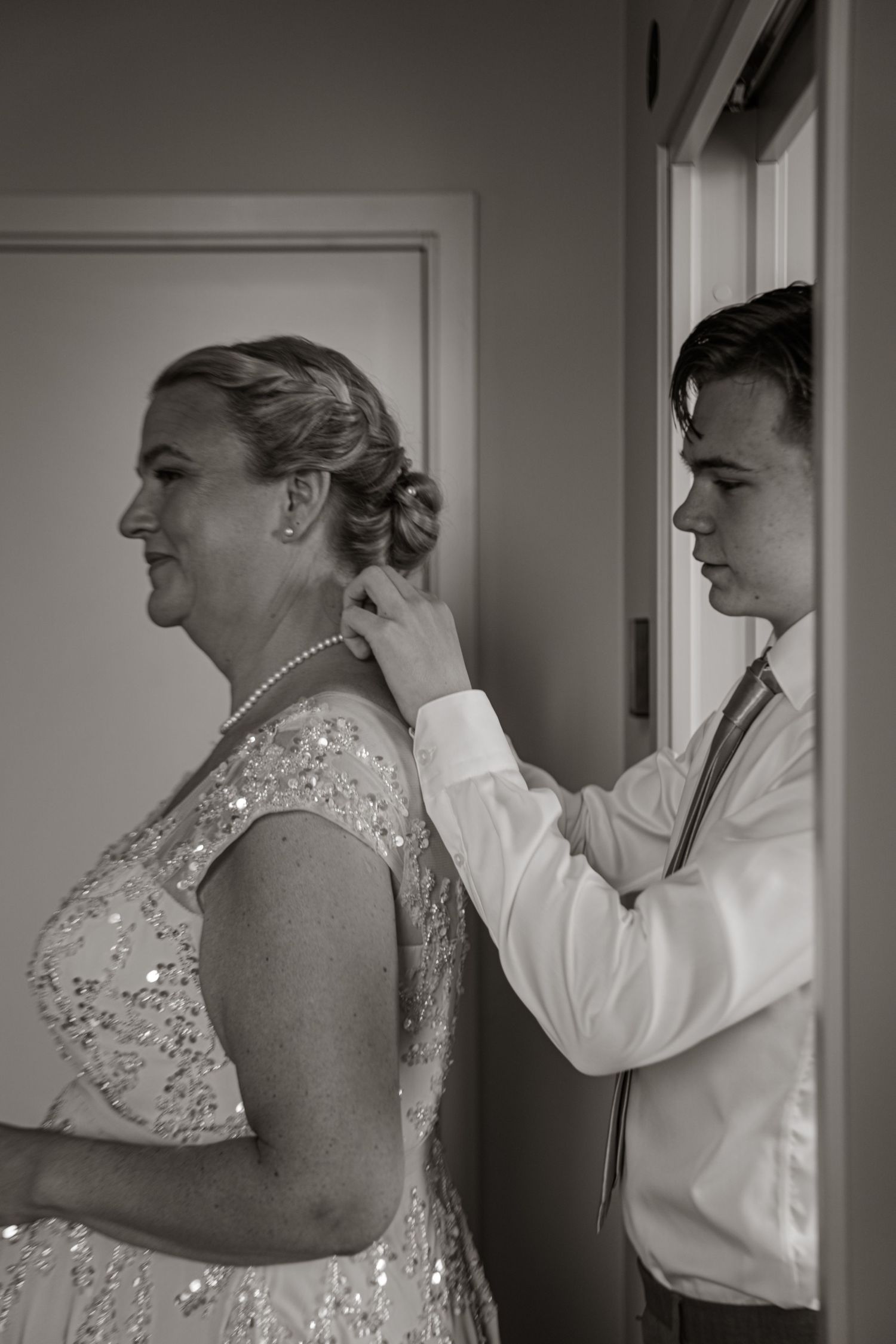 Black and white sequence showing the back view of someone having their hair styled for a formal event.