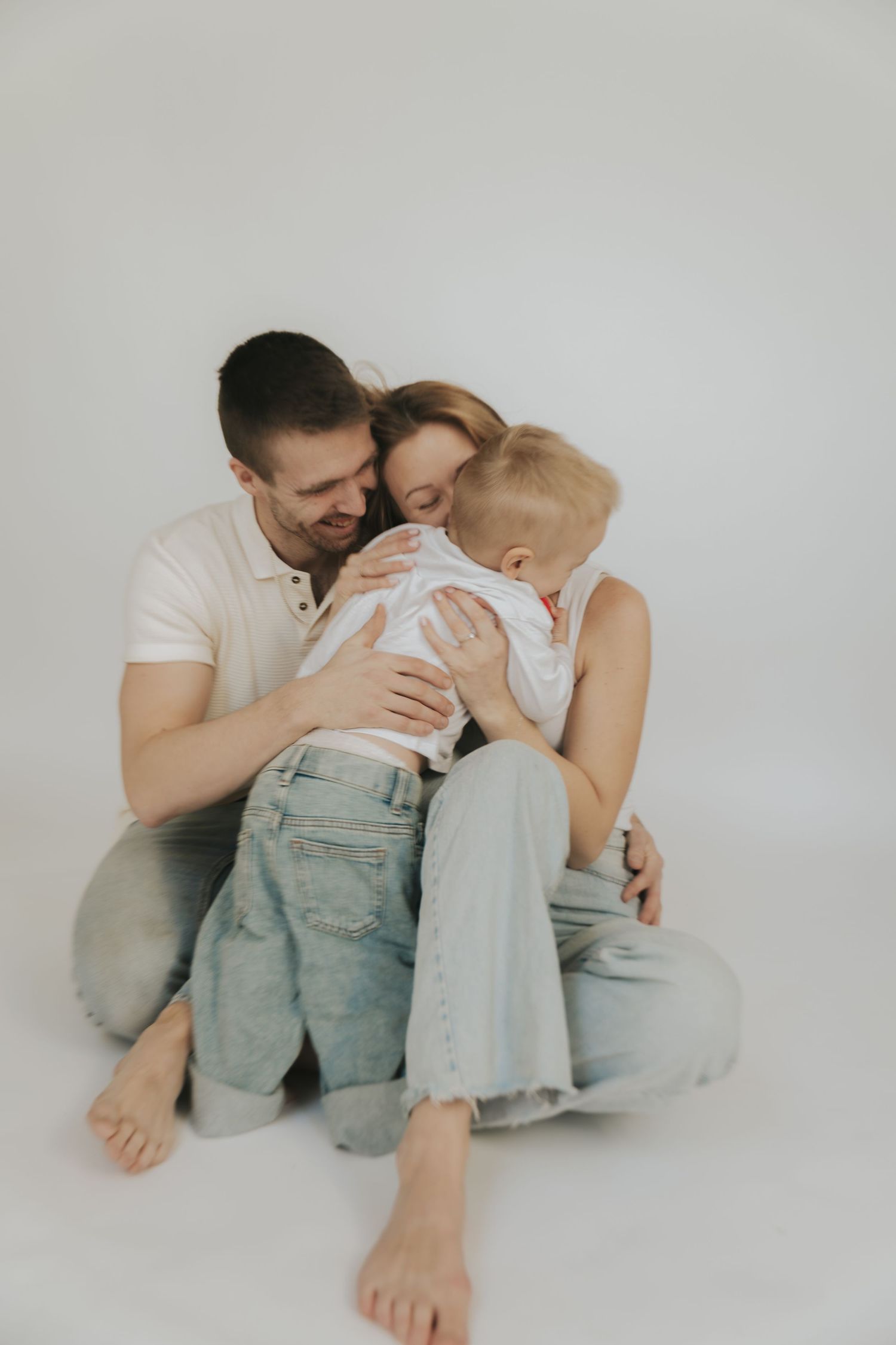 Minimalist family photography series capturing intimate moments on white seamless backdrop.