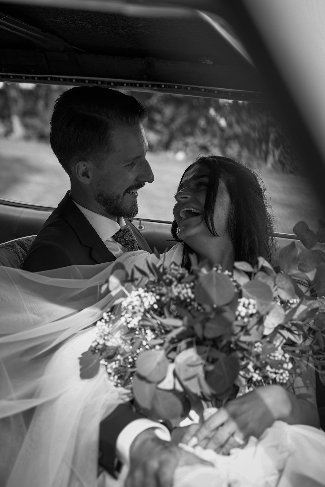 A romantic moment captured in black and white of a couple in wedding attire with a floral bouquet.