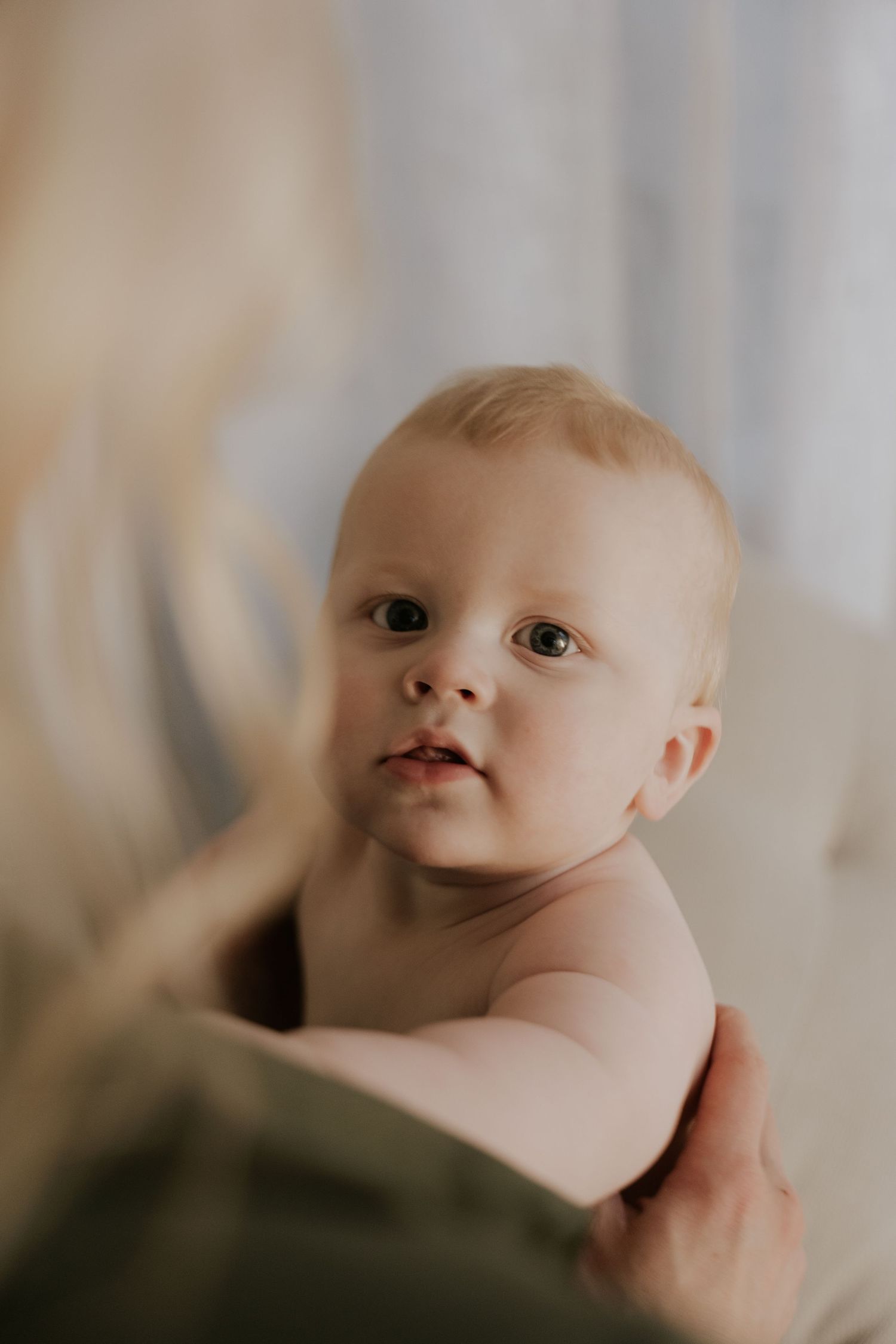 Close-up portrait of an infant with bright eyes and soft features in natural lighting.