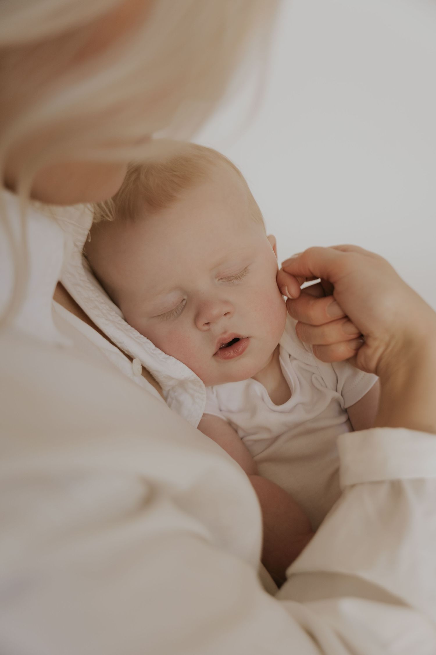 Gentle close-up of sleeping baby being tenderly touched.