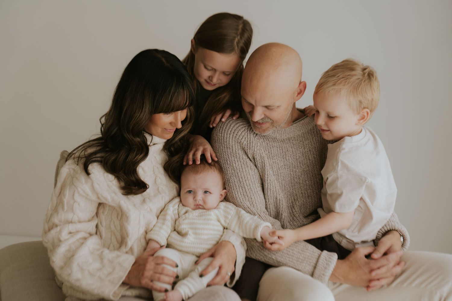 A series of tender black and white photos showing parents cuddling with their baby in intimate home settings.