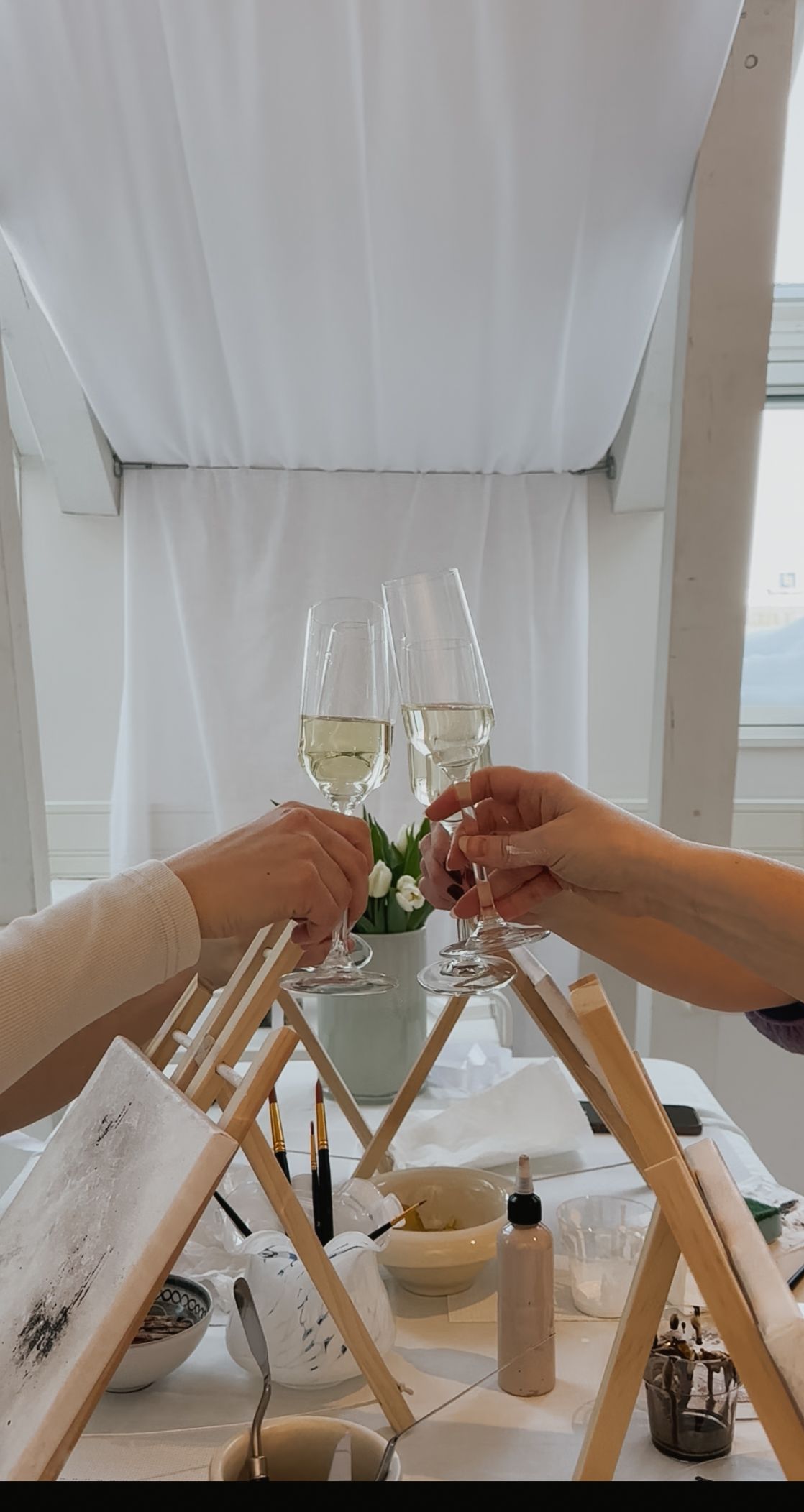 Four connected images showing hands toasting with wine glasses over a white table setting with curtains in background.