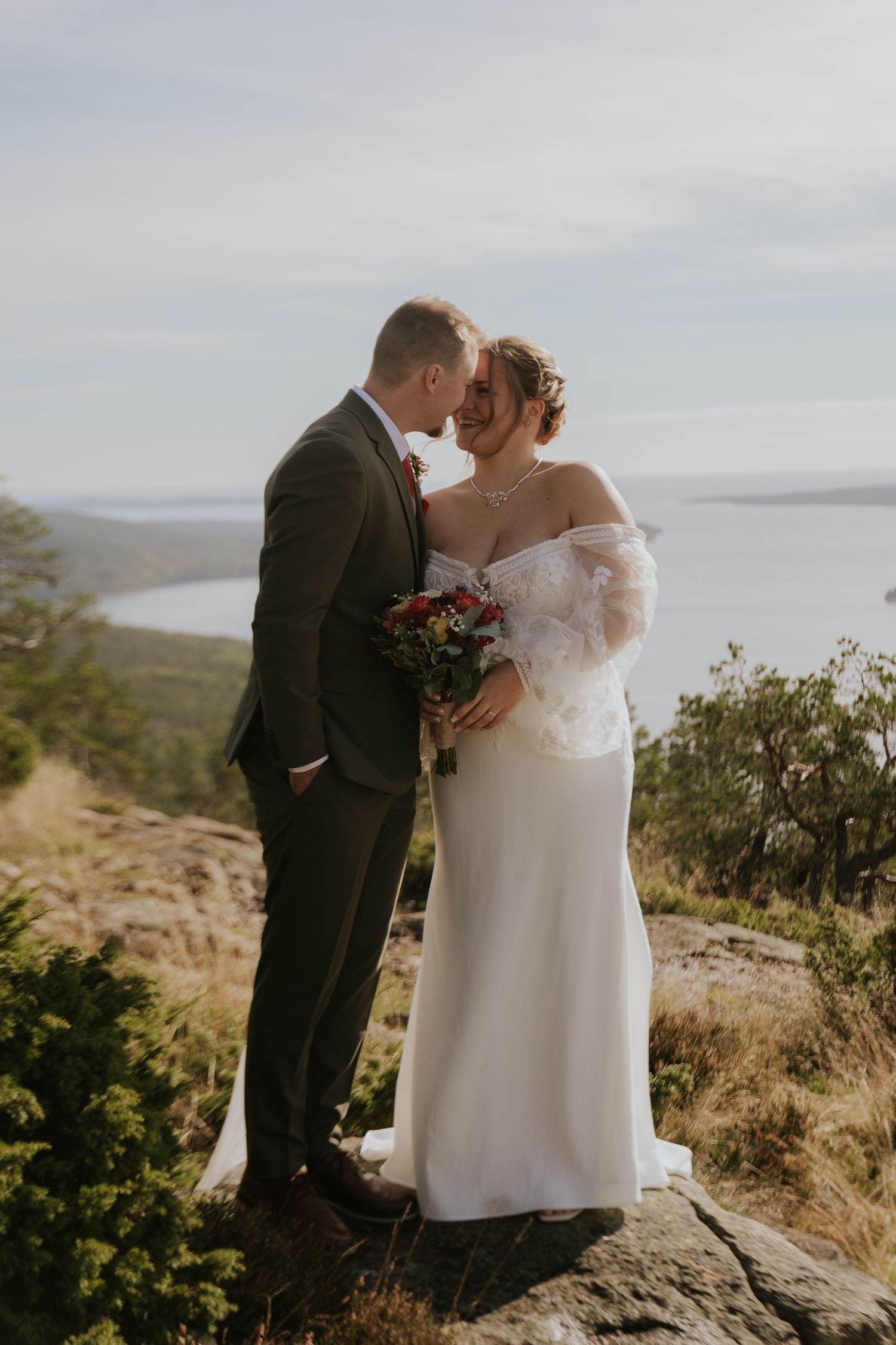A romantic wedding photoshoot on a scenic mountain overlook with dramatic cloudy skies in the background.