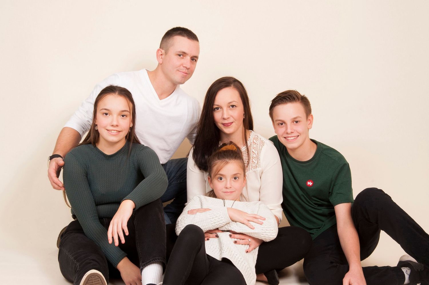 Family of five posing together for a studio portrait against a white background.