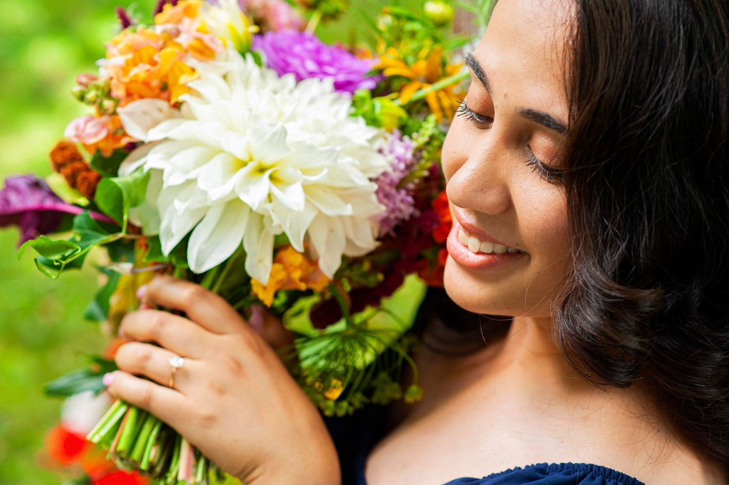 Smiling woman admiring a vibrant bouquet featuring white dahlias and colorful blooms.