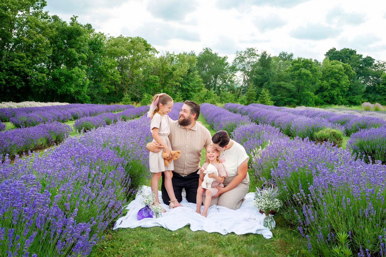 Young family relaxing together on white blanket in a blooming purple lavender field.