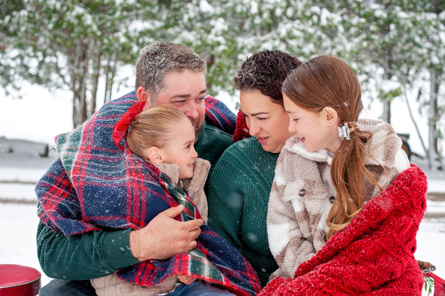 Happy family of four sharing a joyful moment together in the snow.